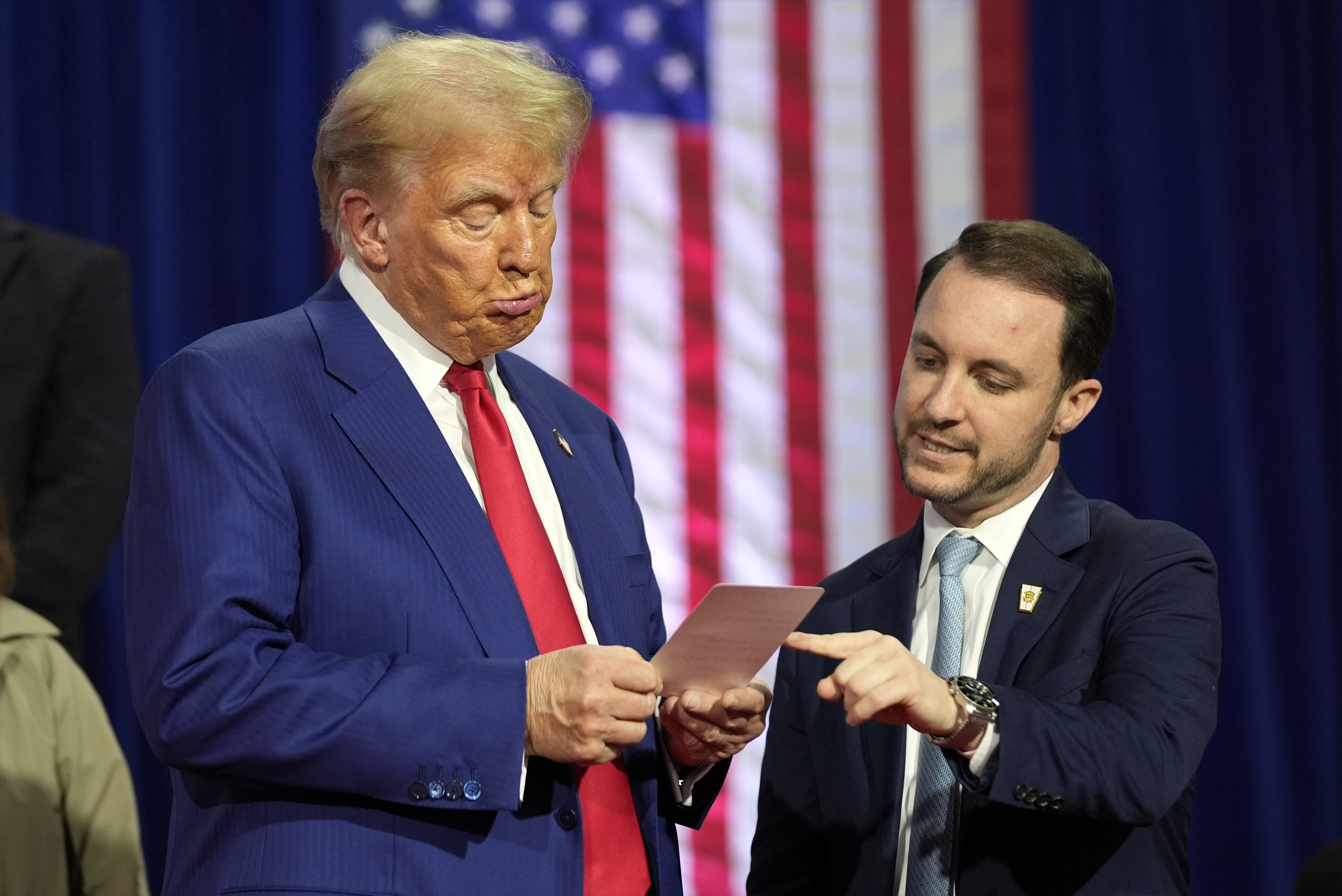 Republican presidential nominee former President Donald Trump reads a note that Justin Caporale brought onto the stage at a campaign town hall at the Greater Philadelphia Expo Center & Fairgrounds, Monday, Oct. 14, 2024, in Oaks, Pa. (AP Photo/Alex Brandon)