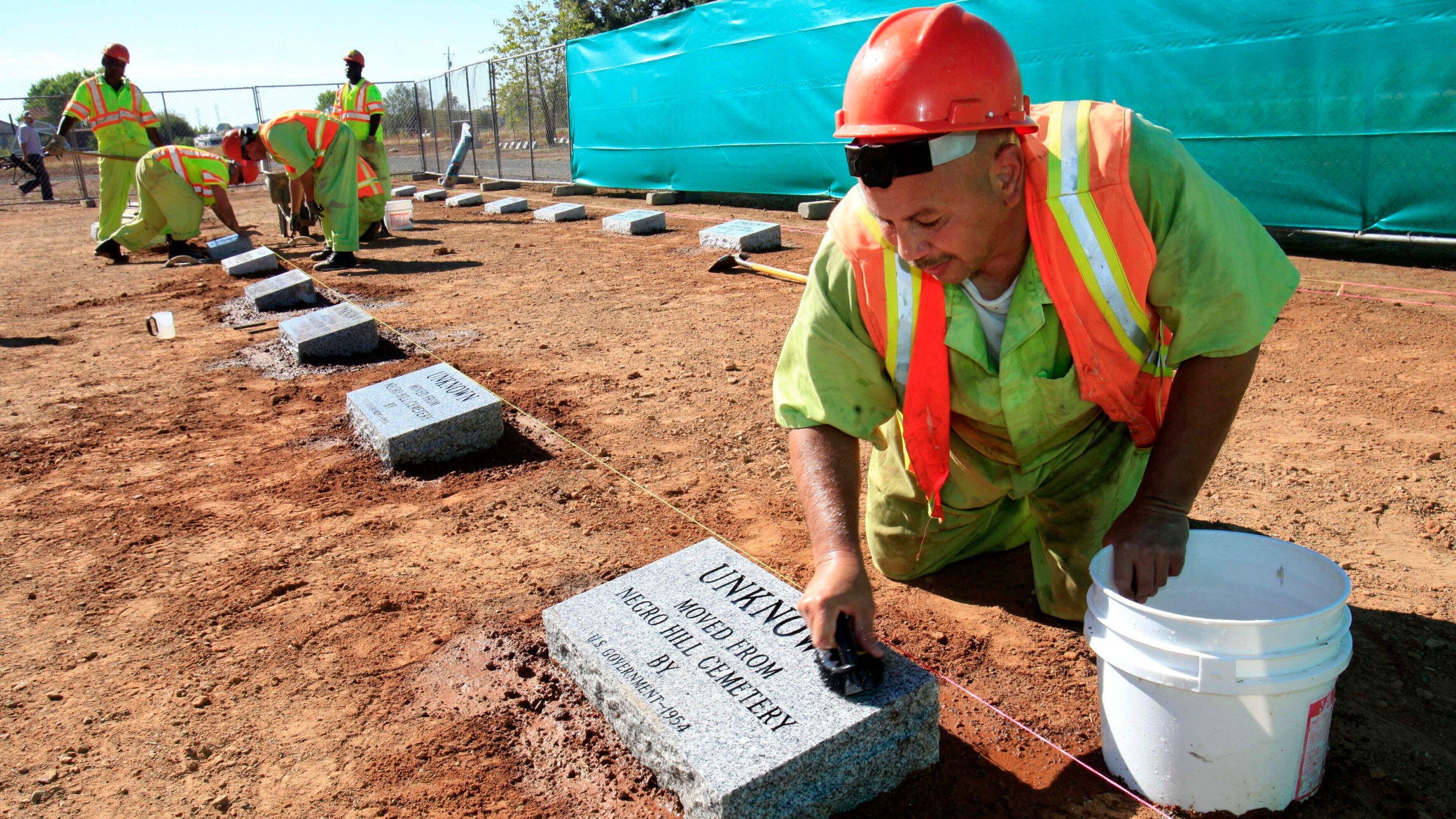 FILE - Steven Abujen, a California prison inmate with the Prison Industry Authority, cleans one of the newly installed headstones at the Mormon Island Relocation Cemetery, near Folsom, Calif., on Oct. 18, 2011. (AP Photo/Rich Pedroncelli, File)