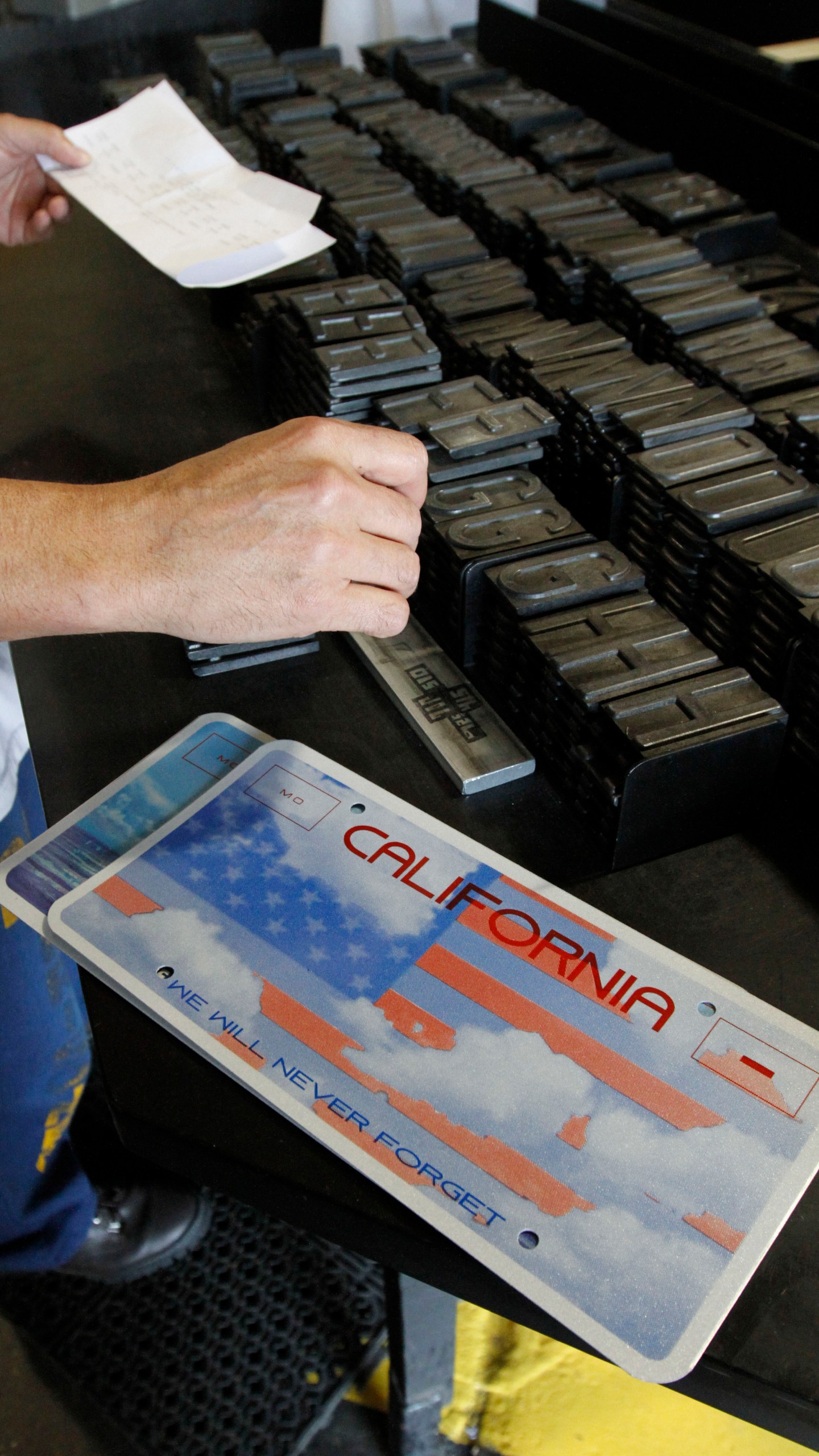 FILE - An inmate selects the letters and numbers to be used to make a specialty license plate by Prison Industries at Folsom State Prison, May 15, 2012, in Folsom, Calif. (AP Photo/Rich Pedroncelli, File)