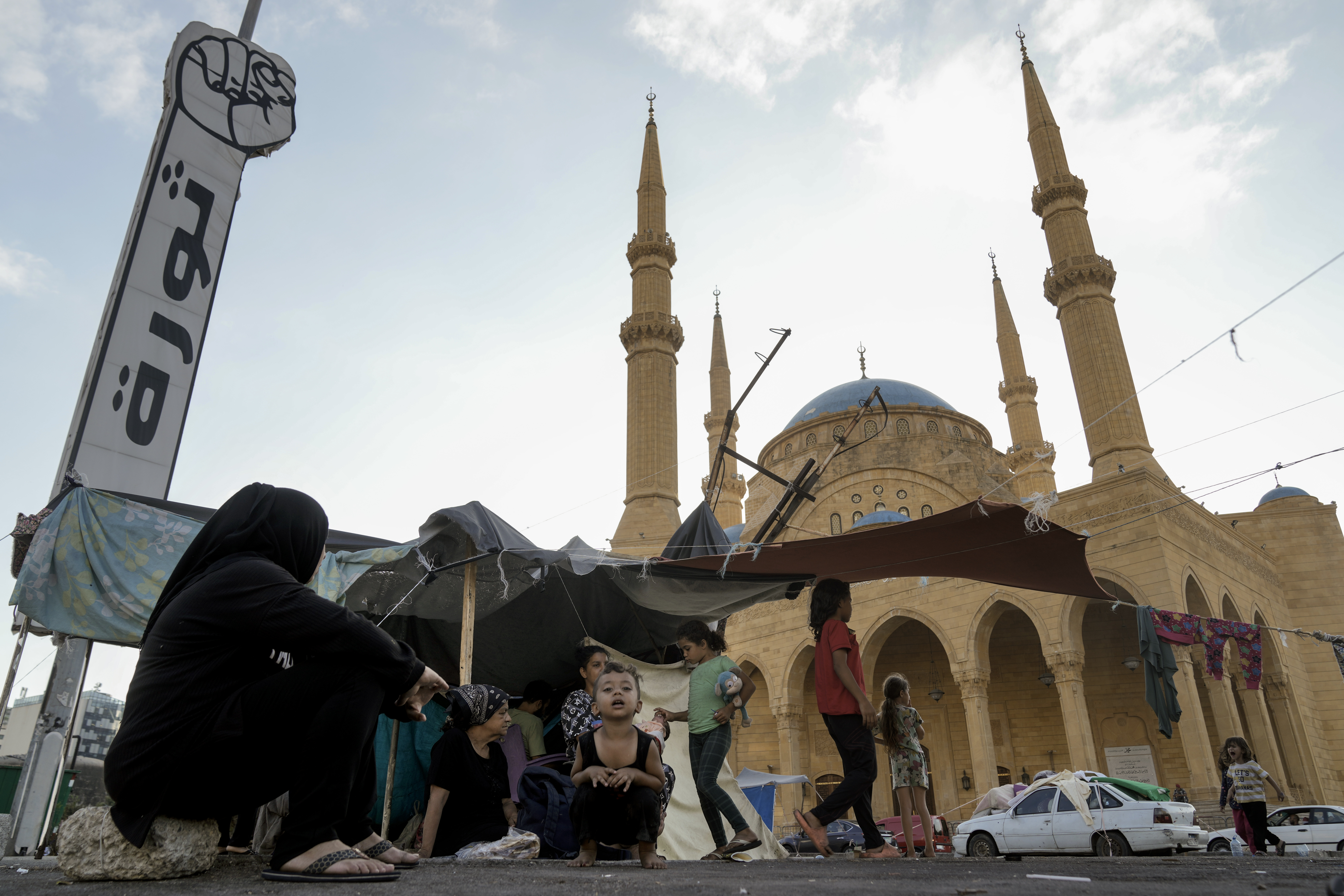 Families fleeing the Israeli airstrikes in the south, sit in front of the Mohammad al-Amin Mosque in downtown Beirut, Lebanon, Monday, Oct. 14, 2024. (AP Photo/Bilal Hussein)