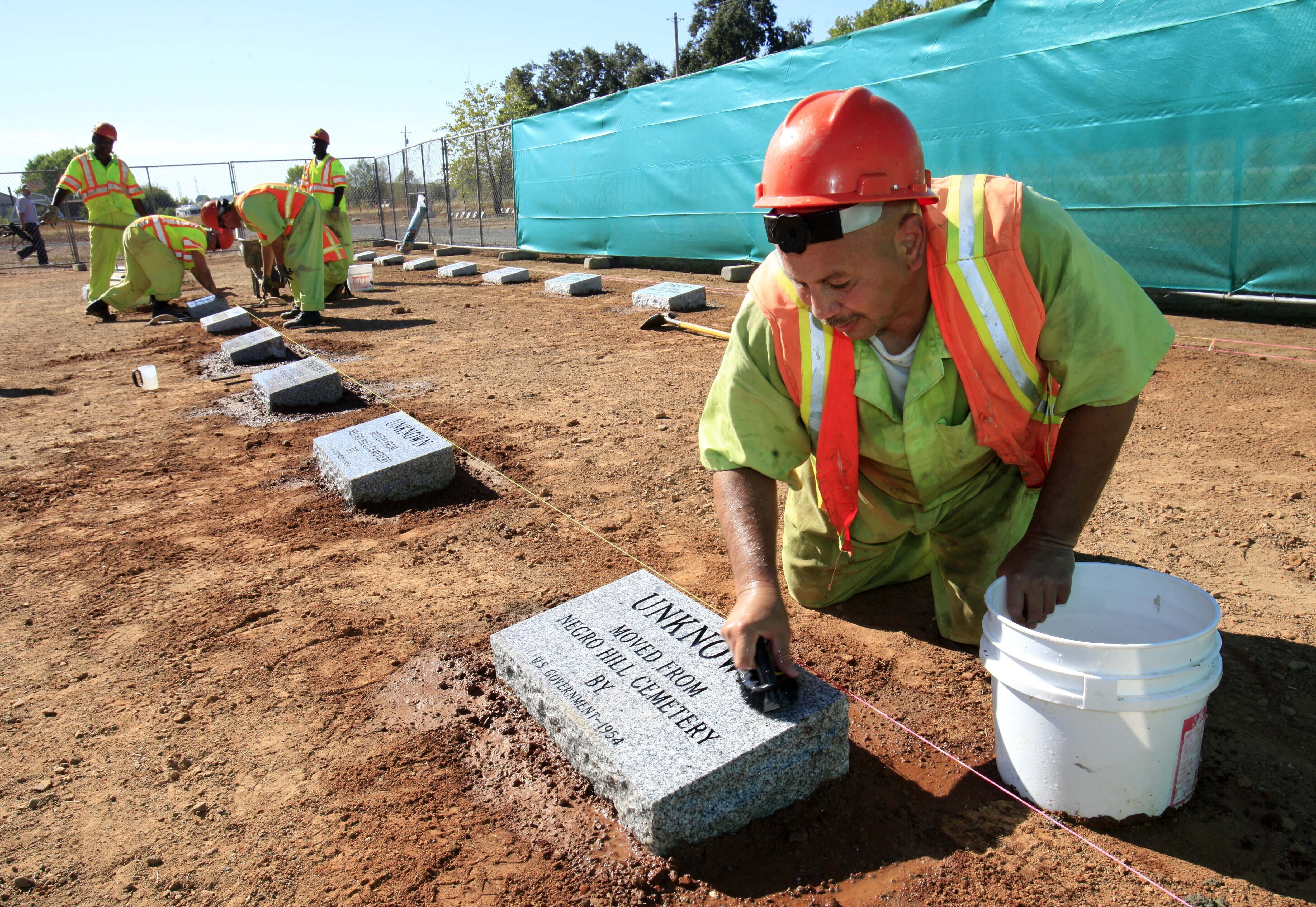 FILE - Steven Abujen, a California prison inmate with the Prison Industry Authority, cleans one of the newly installed headstones at the Mormon Island Relocation Cemetery, near Folsom, Calif., on Oct. 18, 2011. (AP Photo/Rich Pedroncelli, File)