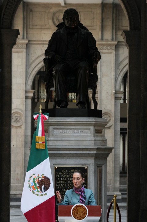 Mexican President Claudia Sheinbaum gives a news conference at the National palace in Mexico City, Tuesday, Oct. 15, 2024. The statue is of former Mexican President Benito Juarez. (AP Photo/Fernando Llano)