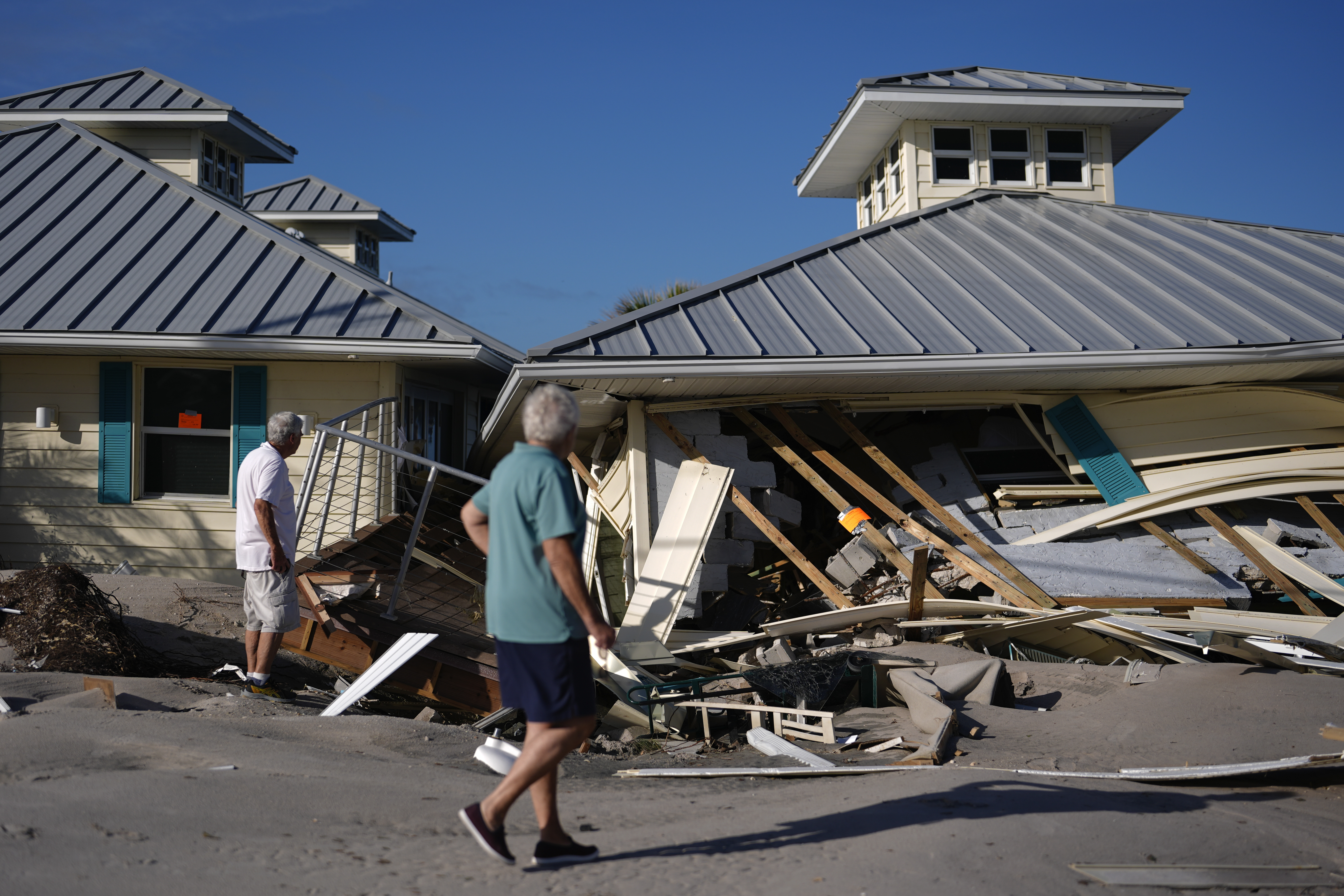 Property owners who preferred not to be named assess damage to their home and business, which bears orange notices calling for demolition, after the passage of Hurricane Milton, on Manasota Key in Englewood, Fla., Sunday, Oct. 13, 2024. (AP Photo/Rebecca Blackwell)