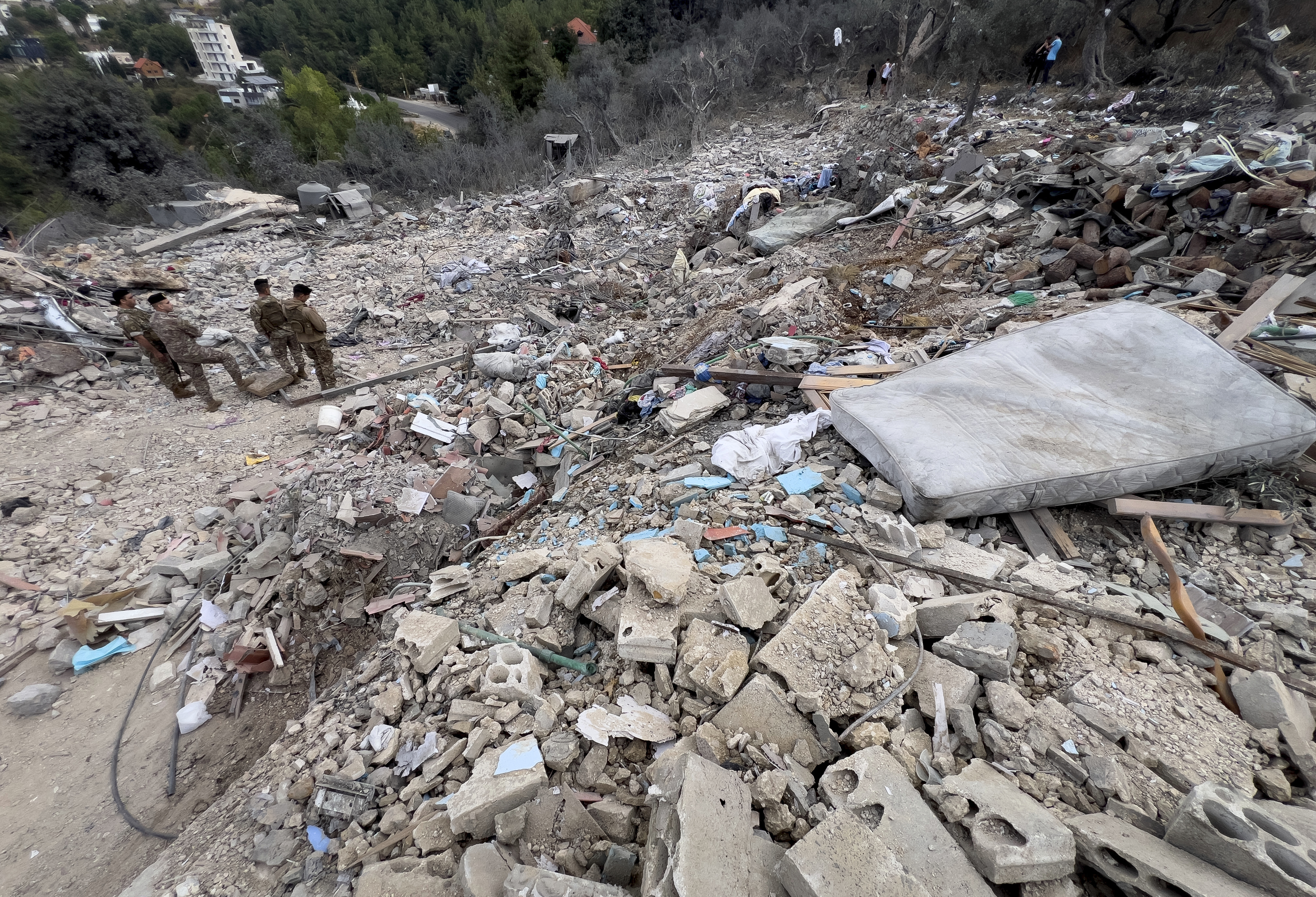 Lebanese army soldiers stand on the rubble of a destroyed building at the site of Monday's Israeli airstrike in the village of Aito, north Lebanon, Tuesday, Oct. 15, 2024. (AP Photo/Hussein Malla)