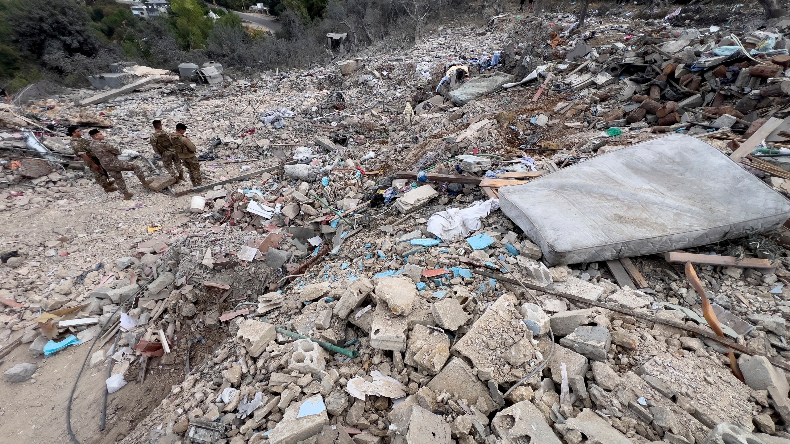 Lebanese army soldiers stand on the rubble of a destroyed building at the site of Monday's Israeli airstrike in the village of Aito, north Lebanon, Tuesday, Oct. 15, 2024. (AP Photo/Hussein Malla)