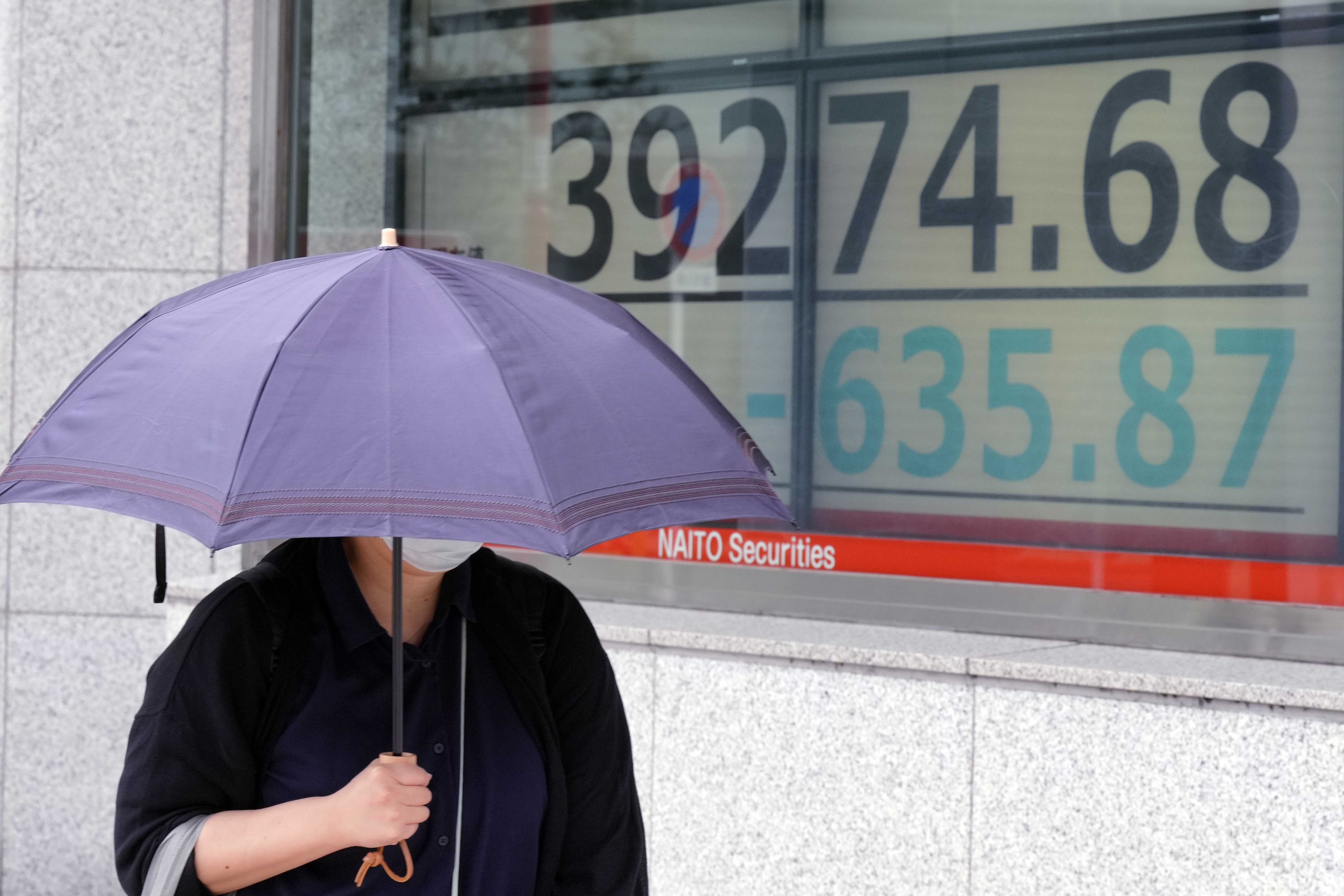 A person walks in front of an electronic stock board showing Japan's Nikkei index at a securities firm Wednesday, Oct. 16, 2024, in Tokyo. (AP Photo/Eugene Hoshiko)