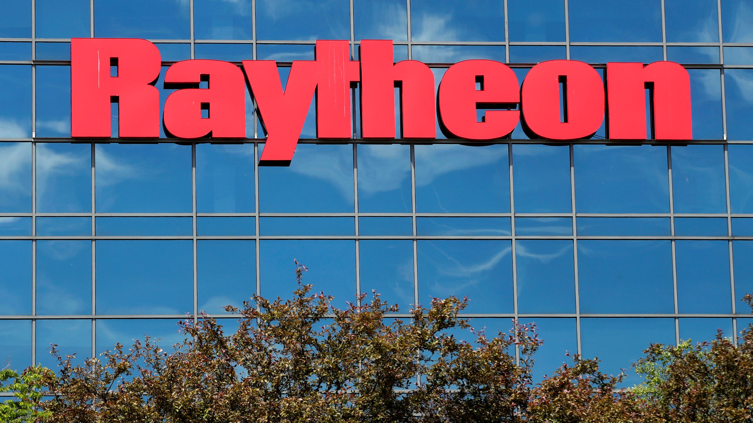 FILE - The sky is reflected on the facade of Raytheon's Integrated Defense Systems facility, Monday, June 10, 2019, in Woburn, Mass. (AP Photo/Elise Amendola, File)