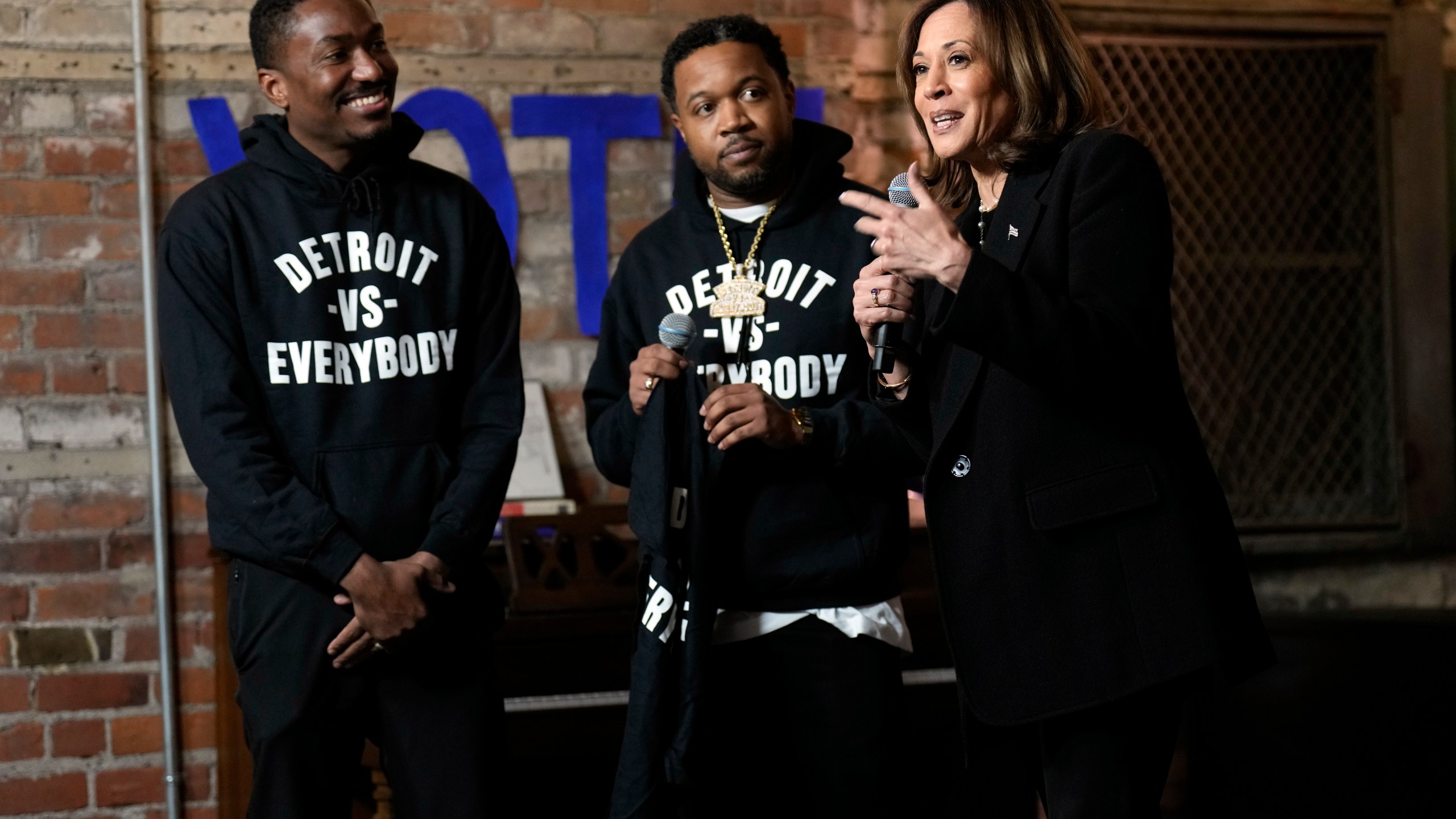 Democratic presidential nominee Vice President Kamala Harris speaks before being presented a shirt by Detroit vs Everybody co-founders Sean Xavier Williams, left, and Tommey Walker, during a stop at Cred Cafe, a local Detroit small business owned by former NBA players Joe and Jamal Crawford, in Detroit, Tuesday, Oct. 15, 2024. (AP Photo/Jacquelyn Martin)