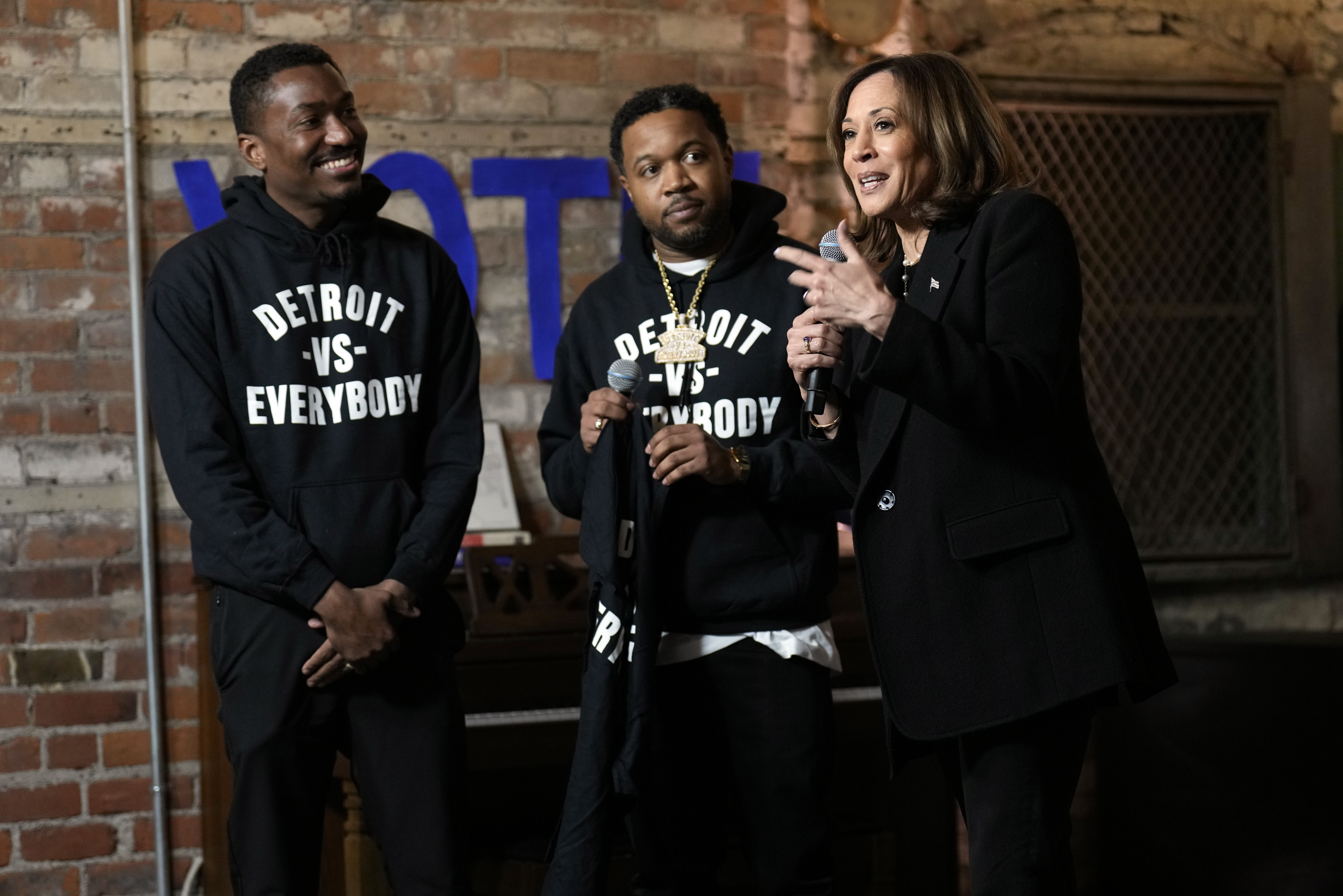 Democratic presidential nominee Vice President Kamala Harris speaks before being presented a shirt by Detroit vs Everybody co-founders Sean Xavier Williams, left, and Tommey Walker, during a stop at Cred Cafe, a local Detroit small business owned by former NBA players Joe and Jamal Crawford, in Detroit, Tuesday, Oct. 15, 2024. (AP Photo/Jacquelyn Martin)