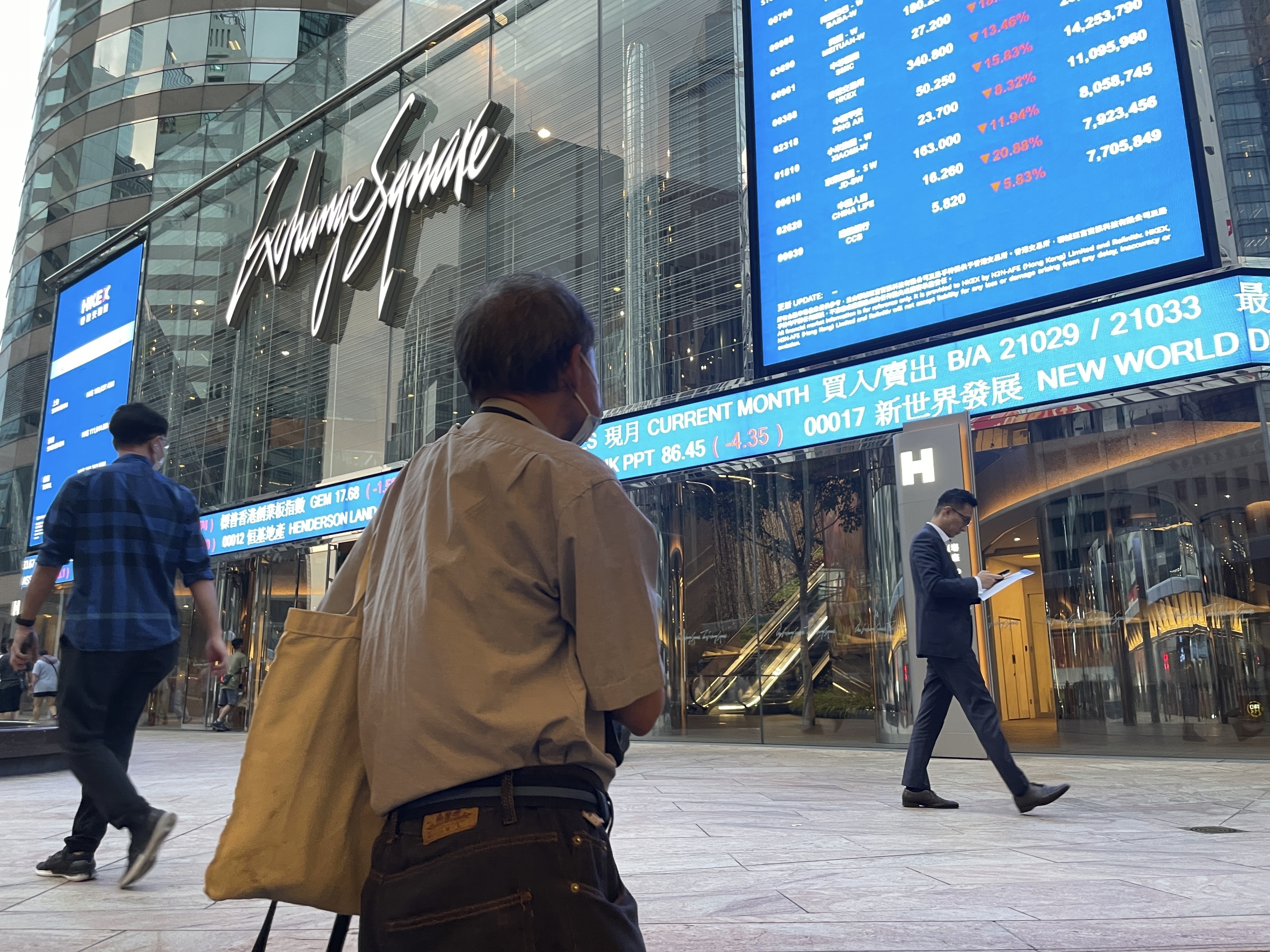 FILE - People walk past Hong Kong's stock exchange building as the market closed with a massive fall of more than nine percent in the benchmark Hang Seng Index, on Oct. 8, 2024. (AP Photo, File)