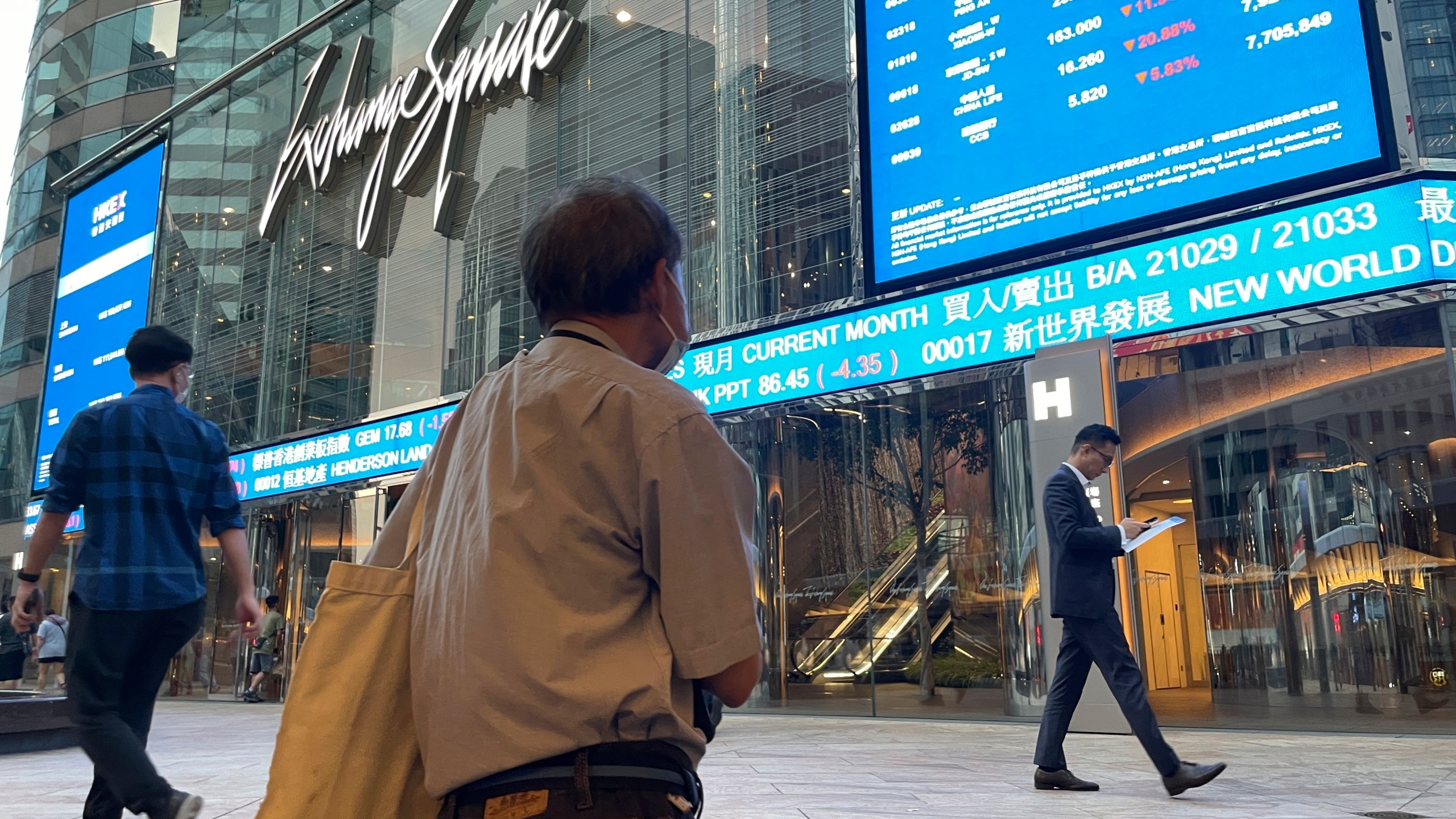 FILE - People walk past Hong Kong's stock exchange building as the market closed with a massive fall of more than nine percent in the benchmark Hang Seng Index, on Oct. 8, 2024. (AP Photo, File)