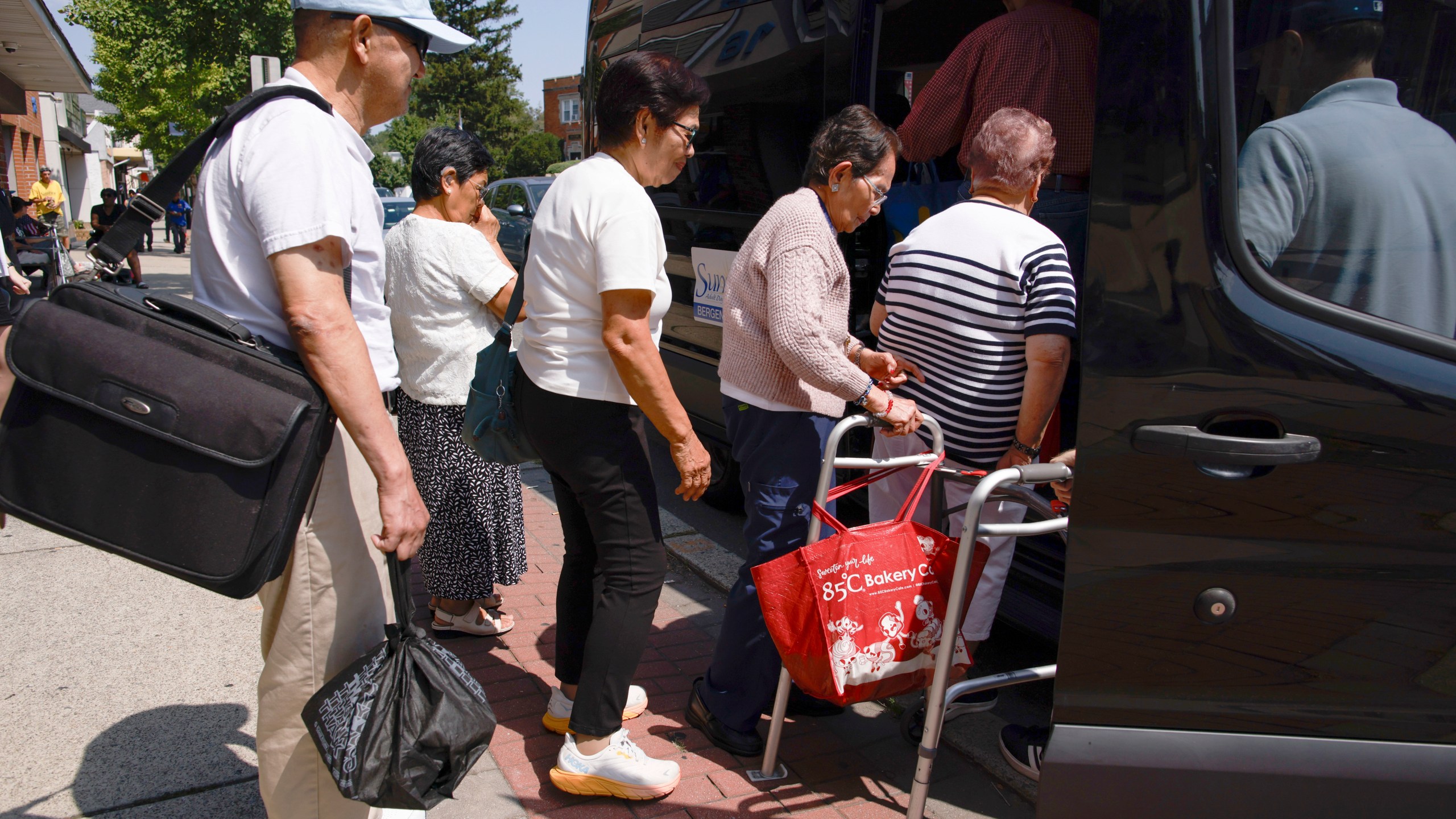 People line up to get into a van to go home outside of Sunshine Adult Day Center in Bergenfield, N.J., Monday, Aug. 26, 2024. (AP Photo/Kena Betancur)