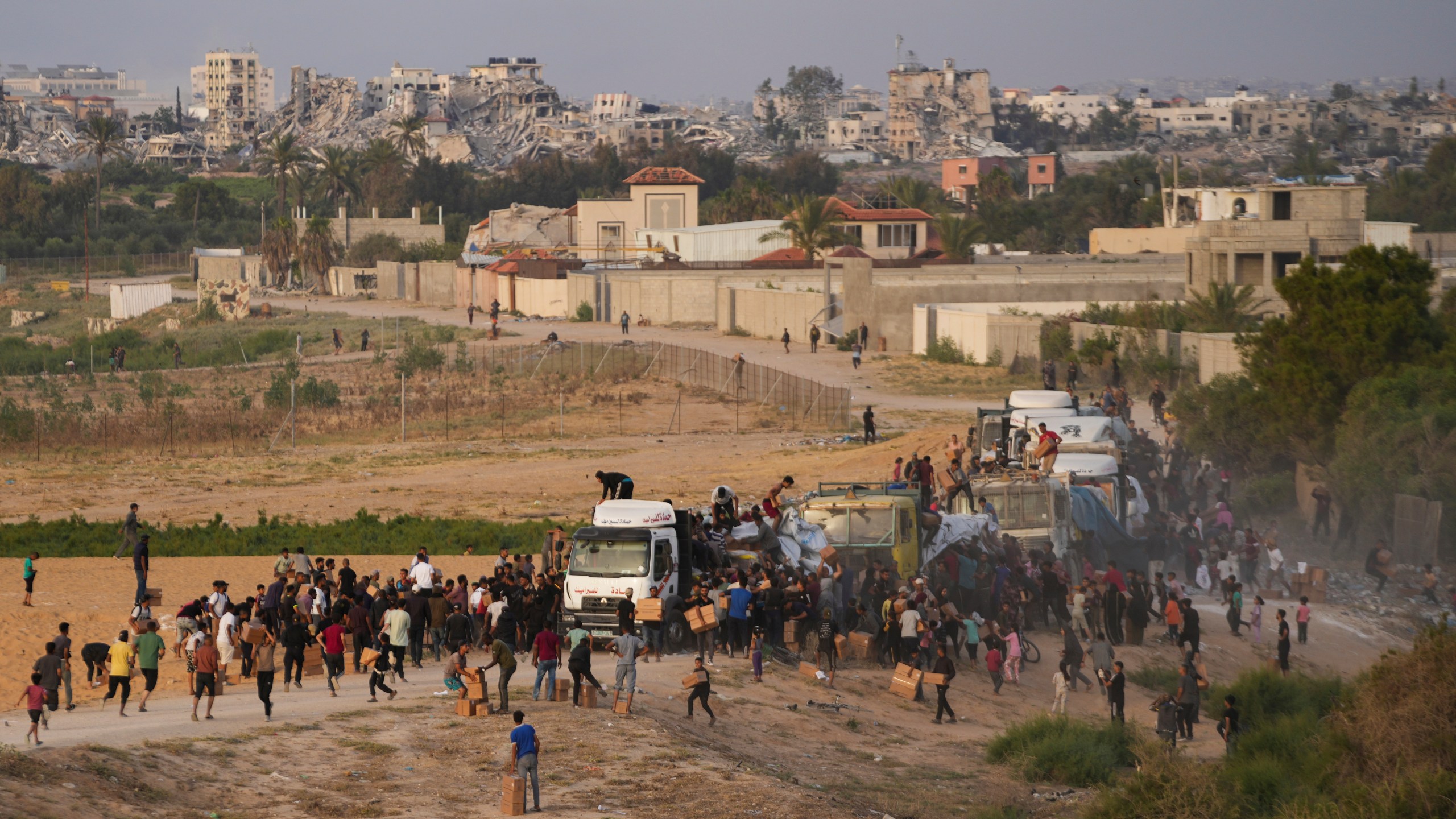 FILE - Palestinians are storming trucks loaded with humanitarian aid brought in through a new U.S.-built pier, in the central Gaza Strip, May 18, 2024. (AP Photo/Abdel Kareem Hana, File)