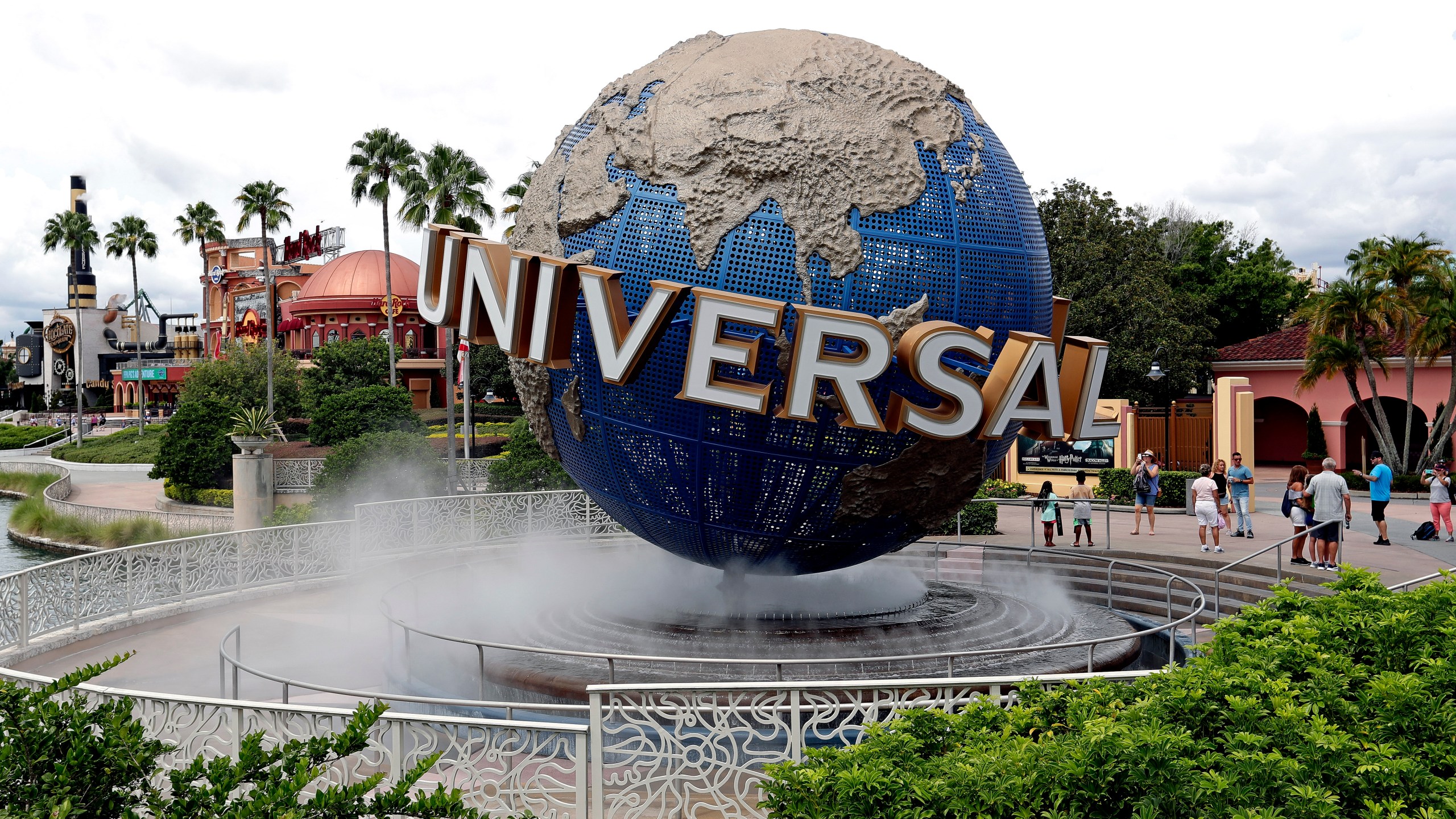 FILE - Guests cool off under a water mist by the globe at Universal Studios City Walk at Universal Studios Florida in Orlando, Fla., Aug. 5, 2019. (AP Photo/John Raoux, File)