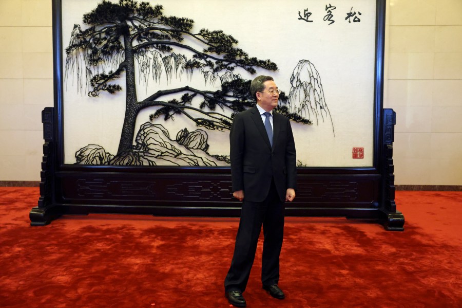 Chinese Vice Premier Ding Xuexiang waits for a handshake with Britain's Foreign Secretary David Lammy at the Great Hall of the People in Beijing Friday, Oct. 18, 2024. (Florence Lo/Pool Photo via AP)