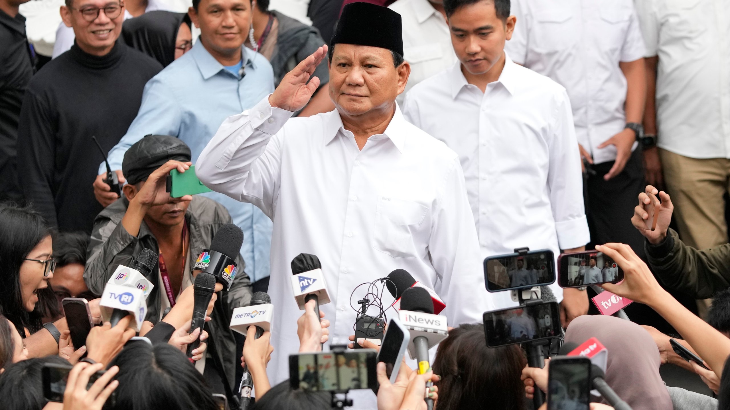 FILE - Indonesian Defense Minister and president-elect Prabowo Subianto, center, salutes to journalists in front of his running mate Gibran Rakabuming Raka, rear center, the eldest son of Indonesian President Joko Widodo, during their formal declaration as president and vice president-elect at the General Election Commission building in Jakarta, Indonesia, Wednesday, April 24, 2024. (AP Photo/Achmad Ibrahim, File)