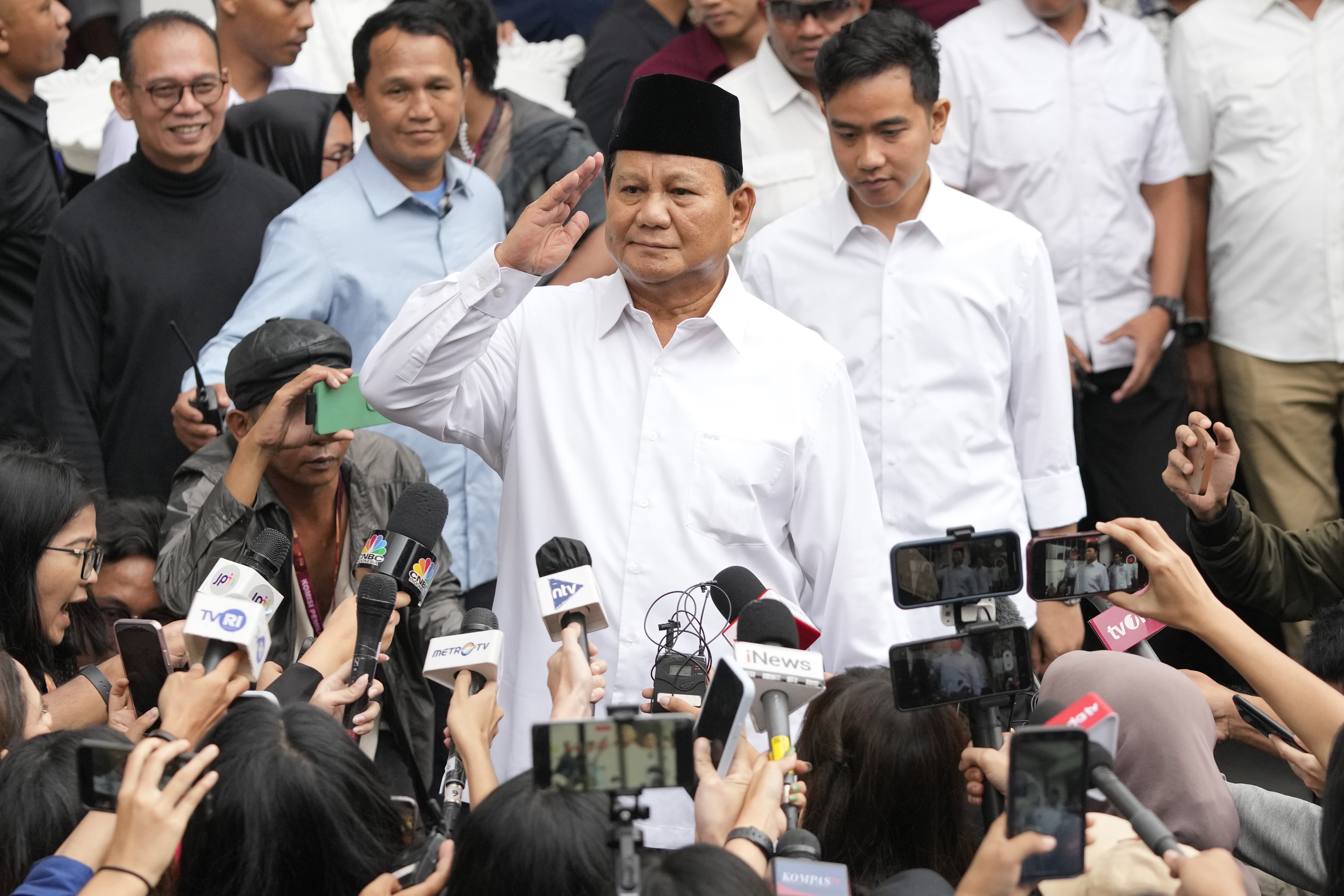 FILE - Indonesian Defense Minister and president-elect Prabowo Subianto, center, salutes to journalists in front of his running mate Gibran Rakabuming Raka, rear center, the eldest son of Indonesian President Joko Widodo, during their formal declaration as president and vice president-elect at the General Election Commission building in Jakarta, Indonesia, Wednesday, April 24, 2024. (AP Photo/Achmad Ibrahim, File)