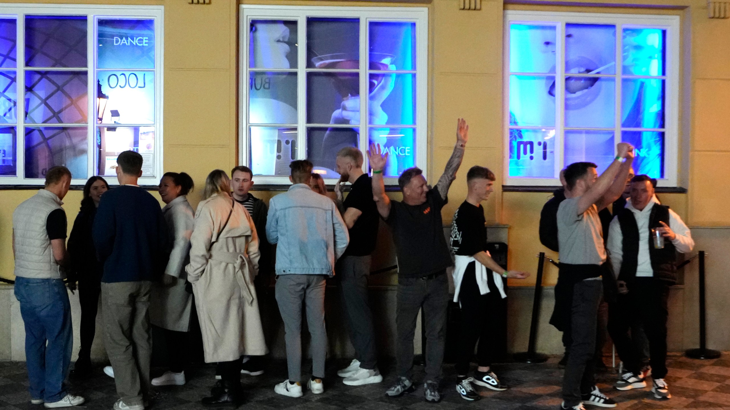 A group of tourists stand in line outside a bar as they attend a pub crawl tour in downtown Prague, Czech Republic, Thursday, Oct. 17, 2024. (AP Photo/Petr David Josek)