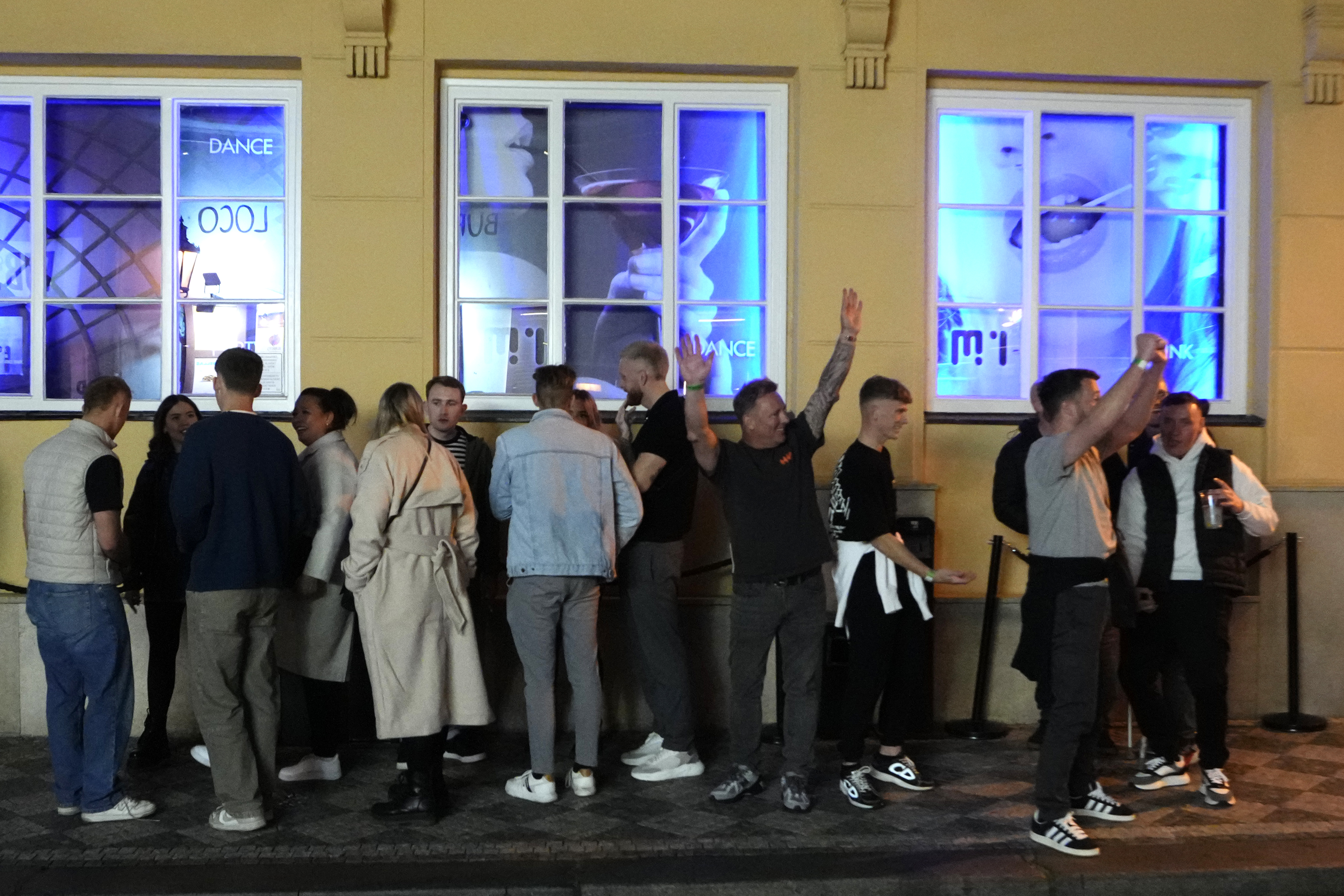 A group of tourists stand in line outside a bar as they attend a pub crawl tour in downtown Prague, Czech Republic, Thursday, Oct. 17, 2024. (AP Photo/Petr David Josek)