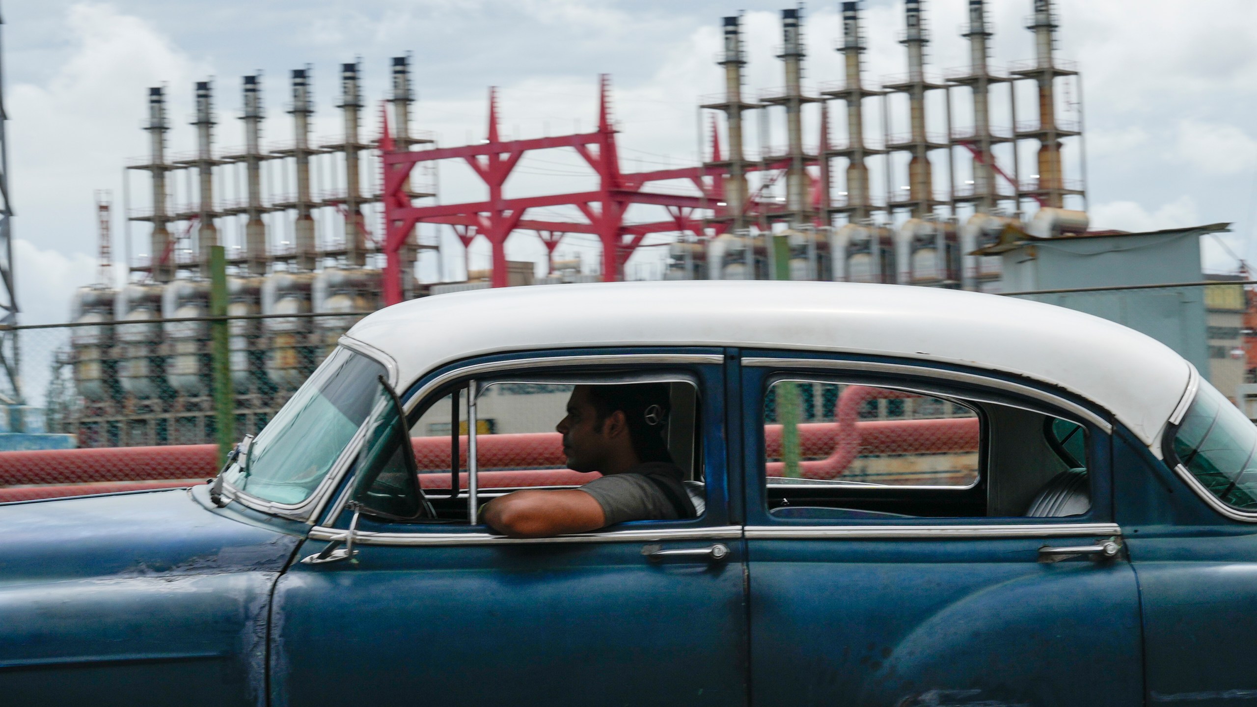 A person drives a classic American car past a floating generator that has not been producing electricity for days in Havana, Cuba, Friday, Oct. 18, 2024. (AP Photo/Ramon Espinosa)