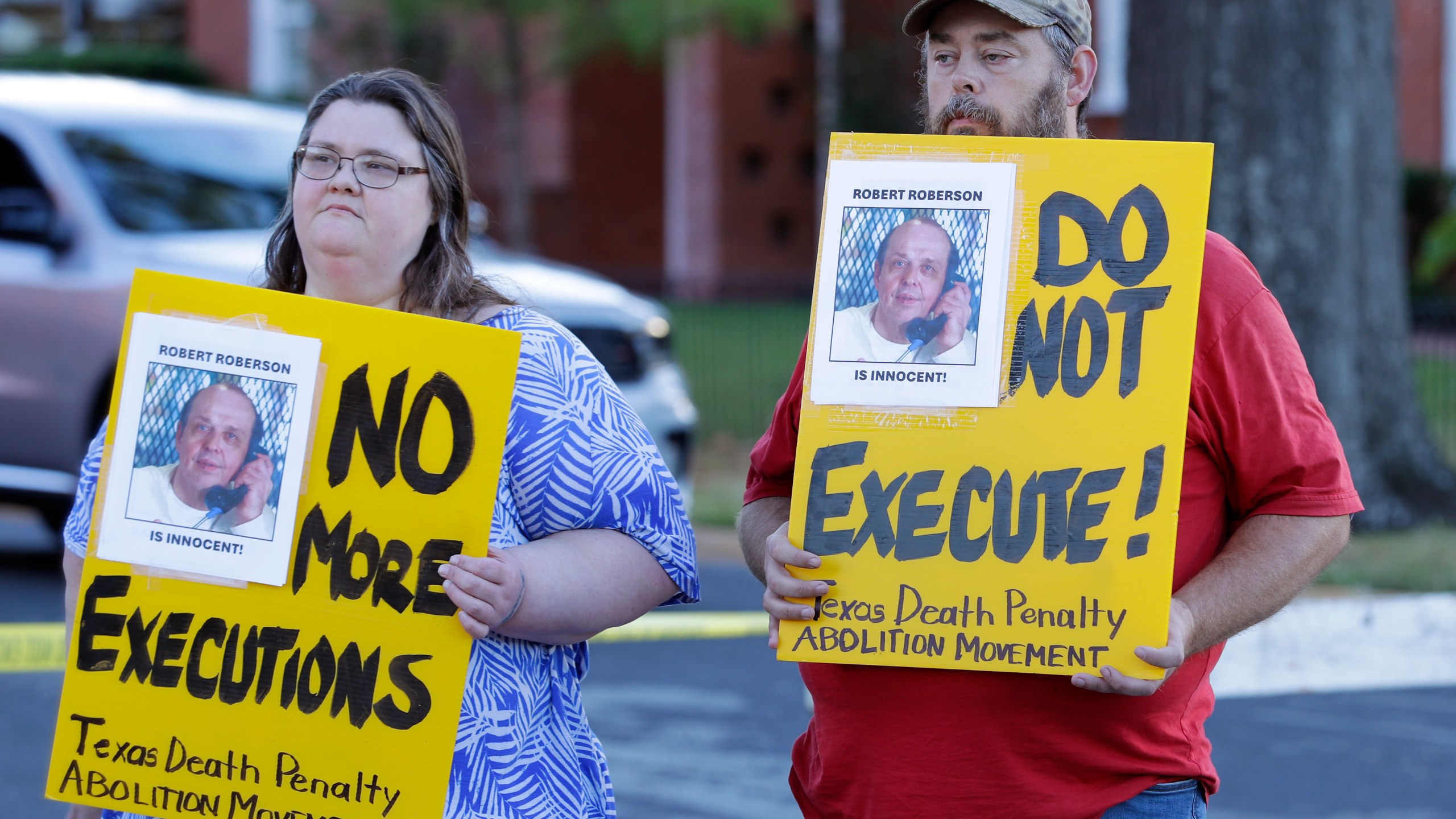 Jennifer Martin, left, and Thomas Roberson, older brother of condemned prisoner Robert Roberson, right, holds signs as they protest outside the prison where Roberson is scheduled for execution at the Huntsville Unit of the Texas State Penitentiary, Thursday, Oct. 17, 2024, in Huntsville, Texas. (AP Photo/Michael Wyke)