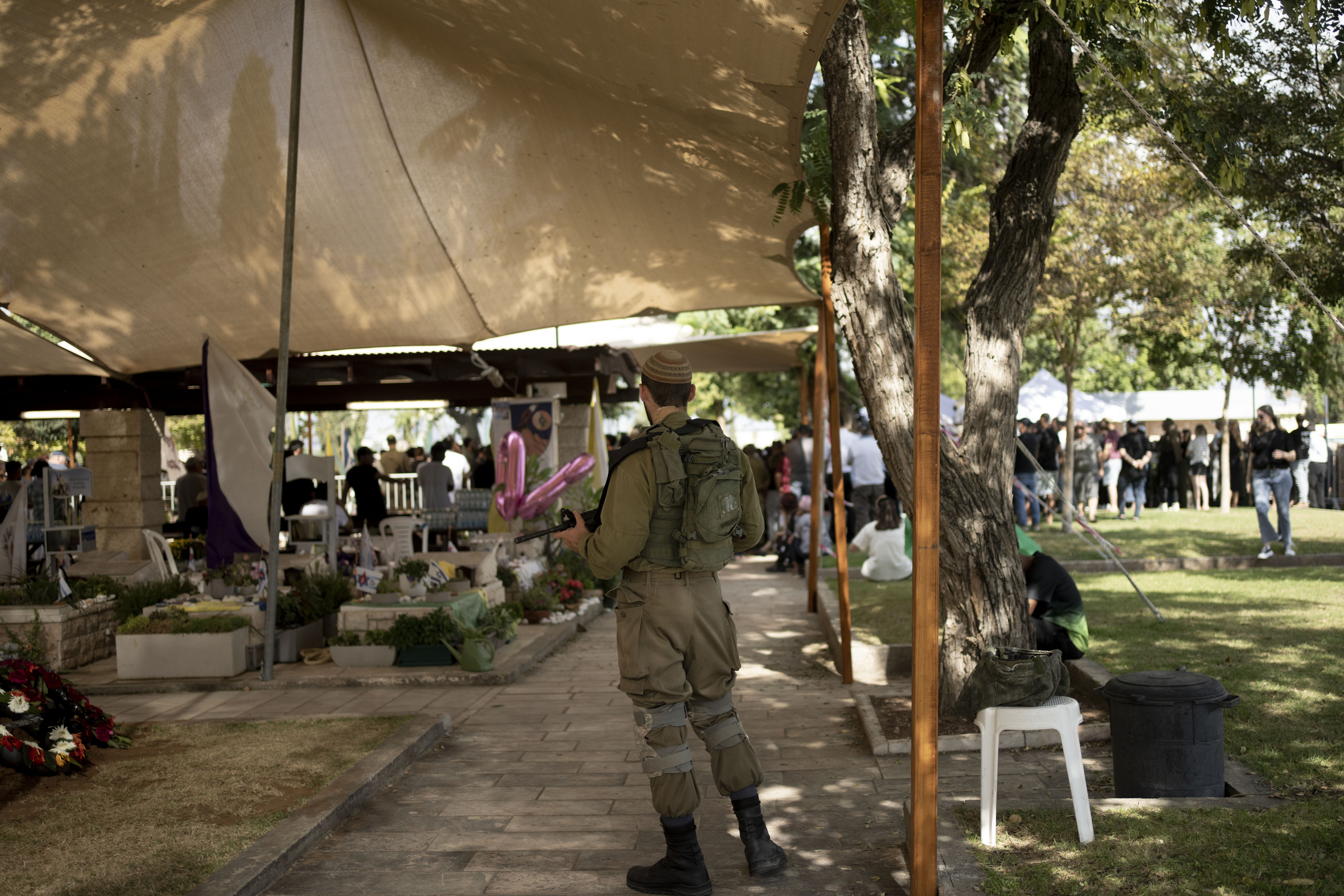 A soldier stands watch as mourners gather for the funeral of Israel Defense Forces Captain Elad Siman Tov, who was killed in action in Lebanon, in Petah Tikva, Israel, Friday, Oct. 18, 2024. (AP Photo/Maya Alleruzzo)