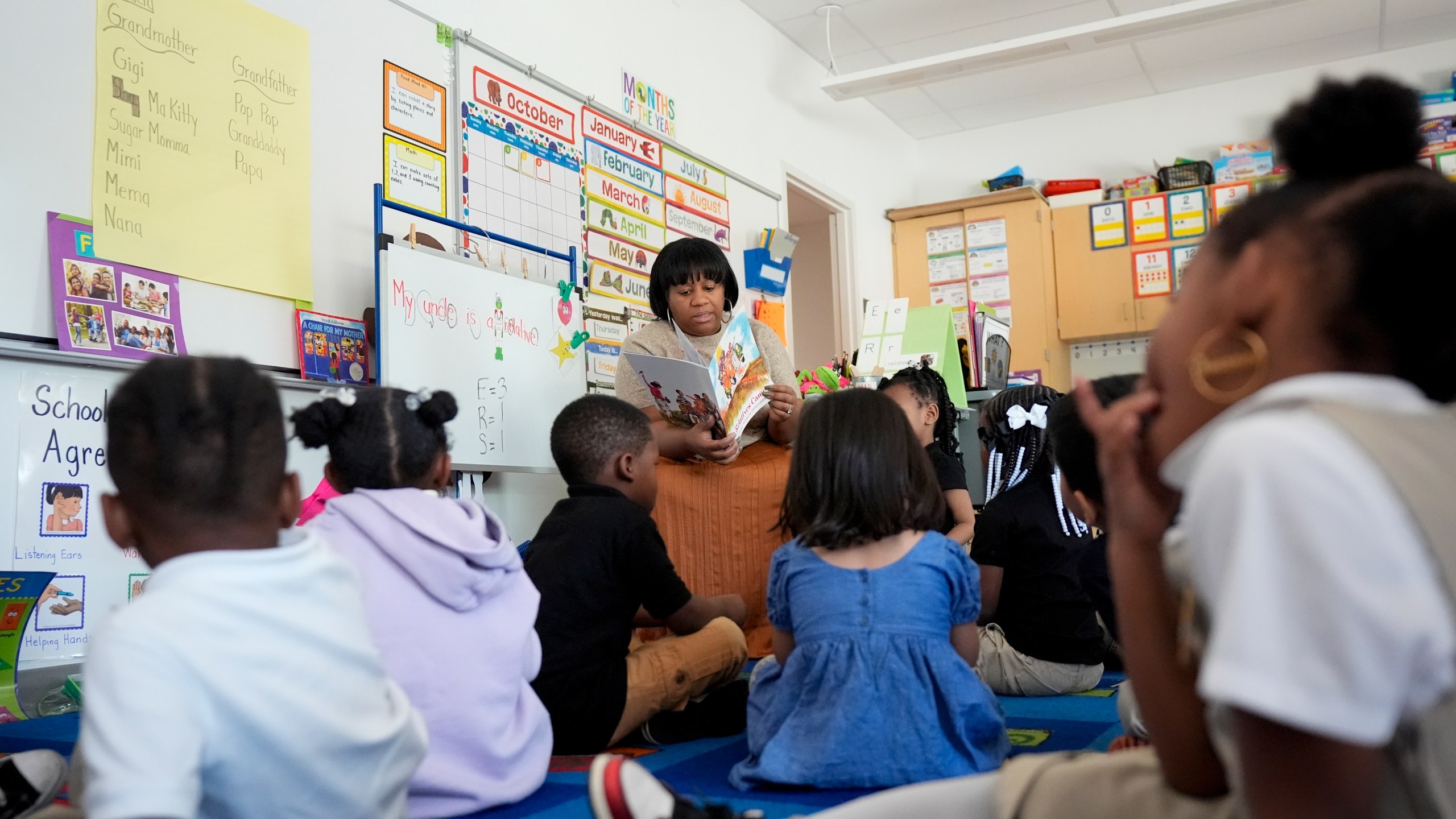 Preschool teacher Bridget Jeffreys reads to students, Thursday, Oct. 3, 2024, at Dorothy I. Height Elementary School in Baltimore. (AP Photo/Stephanie Scarbrough)