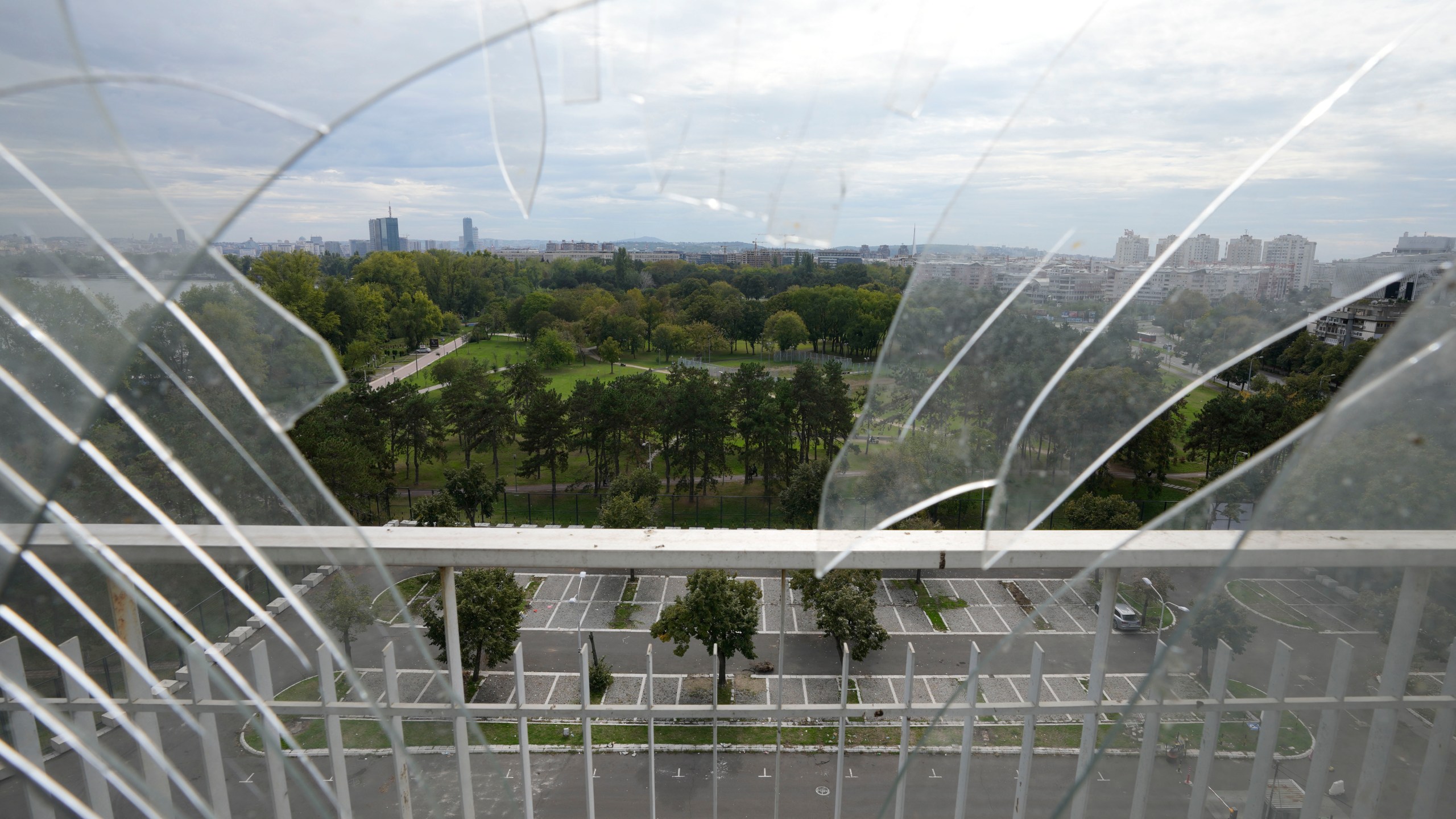 A general view of Belgrade is partially seen through the broken window from Hotel Yugoslavia, once a symbol of progress in the former socialist state of Yugoslavia that broke apart in the 1990s and a favorite gathering place for local residents as well as world leaders, in Belgrade, Serbia, Thursday, Oct. 3, 2024. (AP Photo/Darko Vojinovic)