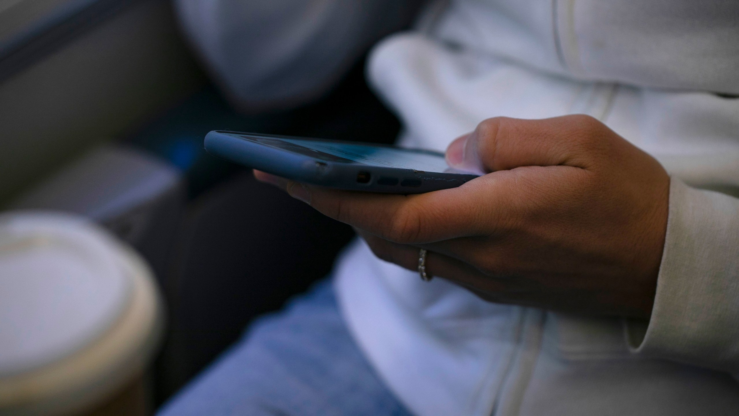 FILE - A woman looks at a hand held device on a train in New Jersey on May 18, 2021. (AP Photo/Jenny Kane, File)