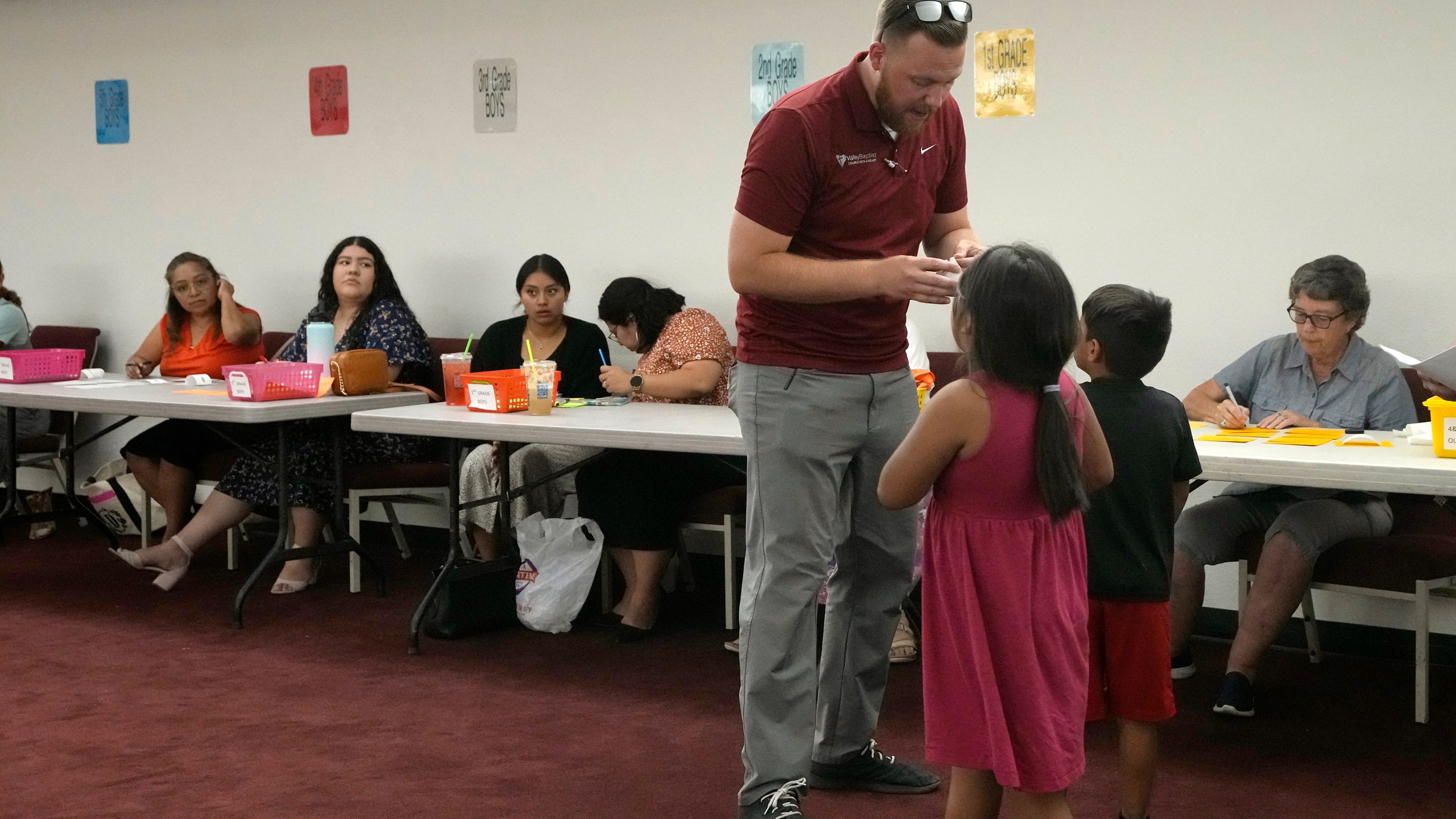 Trevor Cowling helps participants in summer camp find their classes at Valley Baptist Church Tuesday, June 18, 2024, in Mesa, Ariz. (AP Photo/Ross D. Franklin)