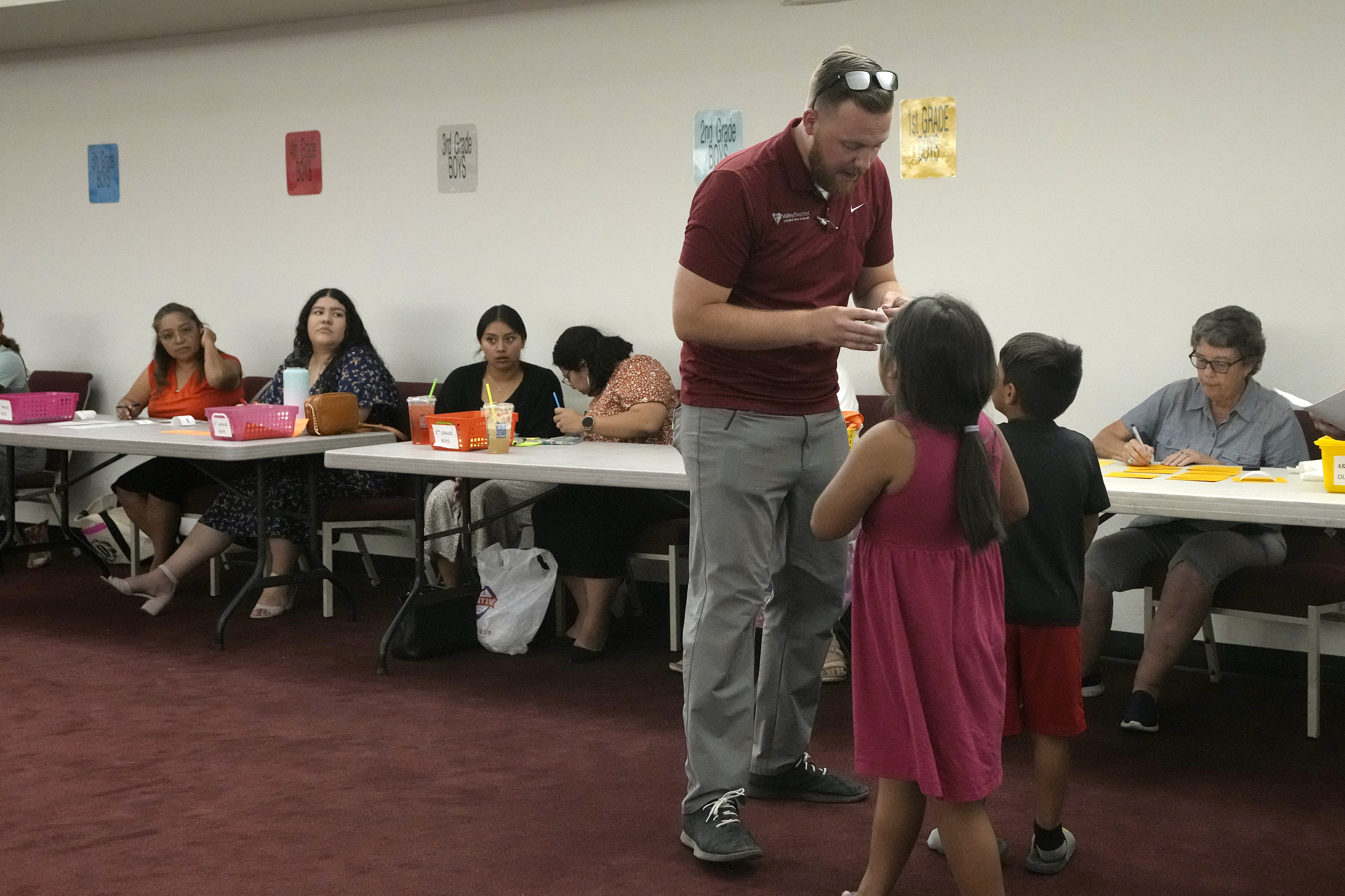 Trevor Cowling helps participants in summer camp find their classes at Valley Baptist Church Tuesday, June 18, 2024, in Mesa, Ariz. (AP Photo/Ross D. Franklin)