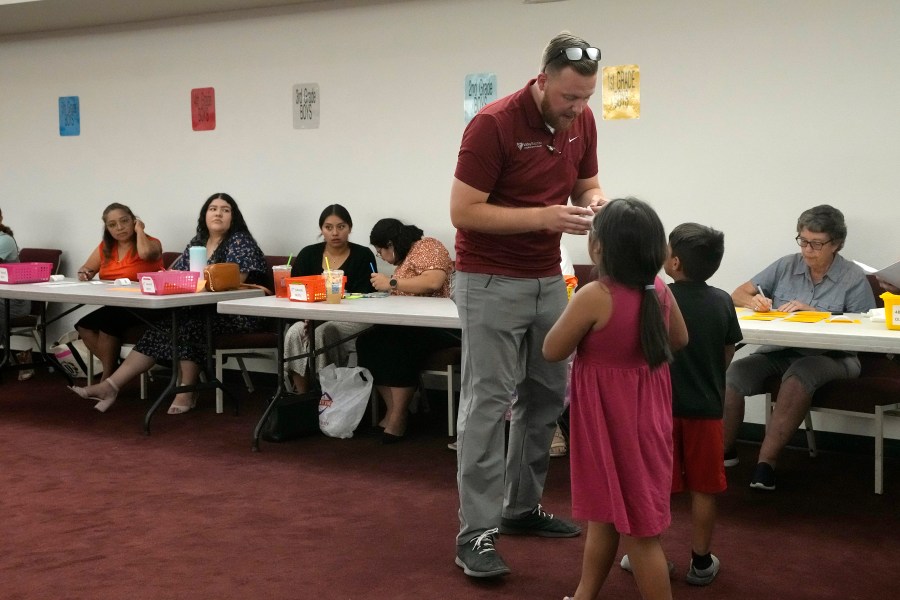 Trevor Cowling helps participants in summer camp find their classes at Valley Baptist Church Tuesday, June 18, 2024, in Mesa, Ariz. (AP Photo/Ross D. Franklin)