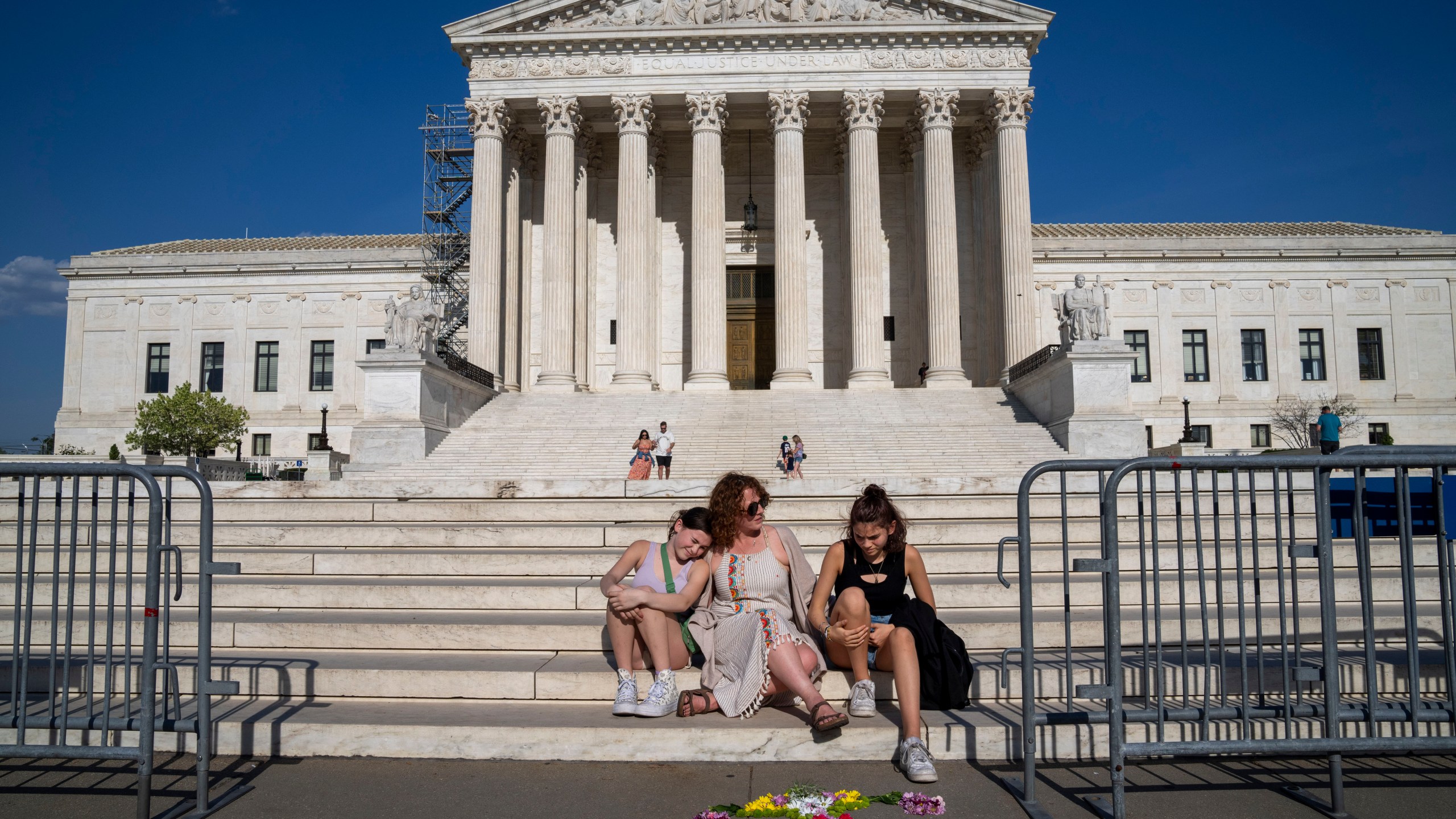 FILE - Krissy Shields, of New York City, talks with her daughters after creating the shape of a uterus out of flowers by the steps of the Supreme Court, April 21, 2023, in Washington. (AP Photo/Jacquelyn Martin, File)