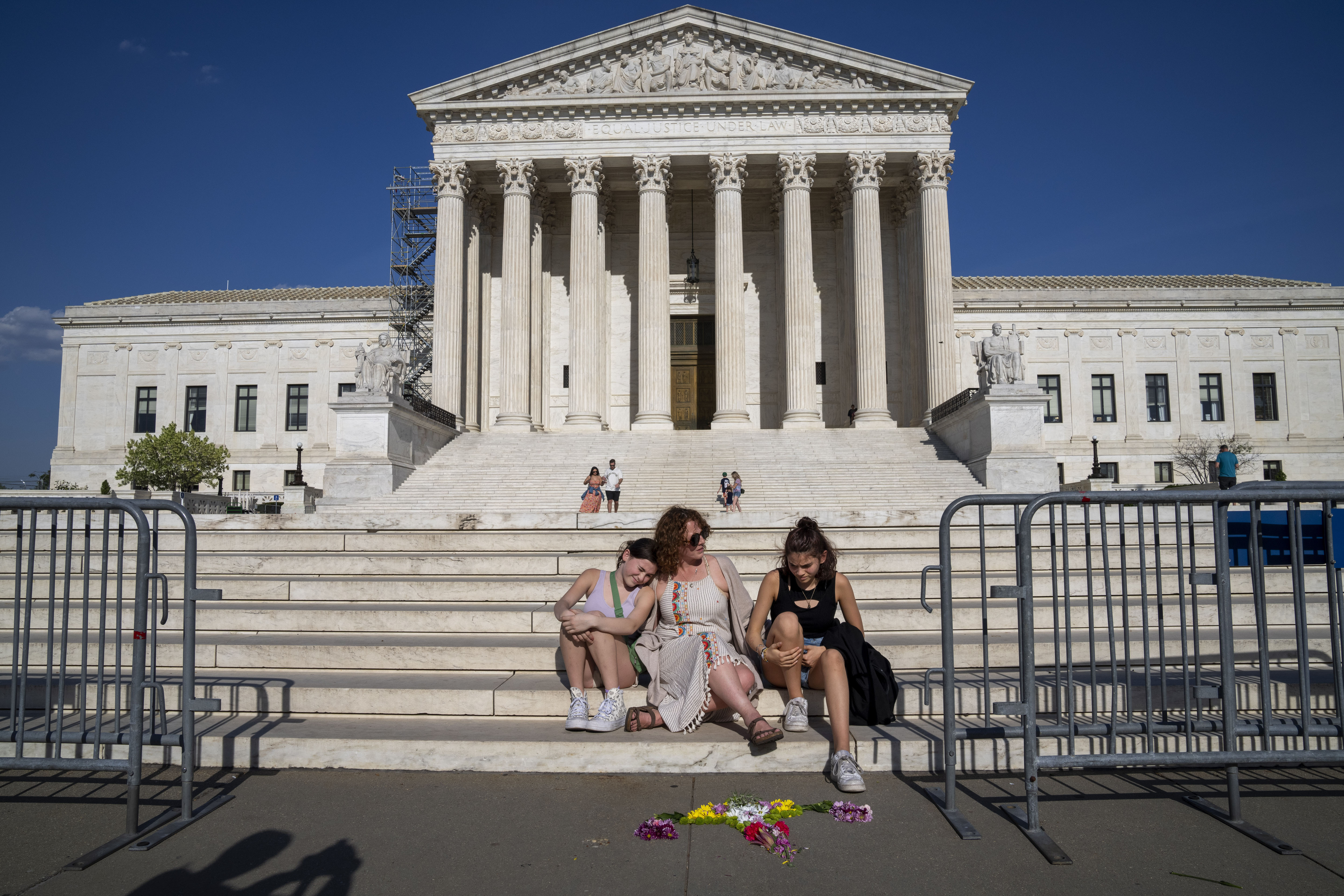 FILE - Krissy Shields, of New York City, talks with her daughters after creating the shape of a uterus out of flowers by the steps of the Supreme Court, April 21, 2023, in Washington. (AP Photo/Jacquelyn Martin, File)