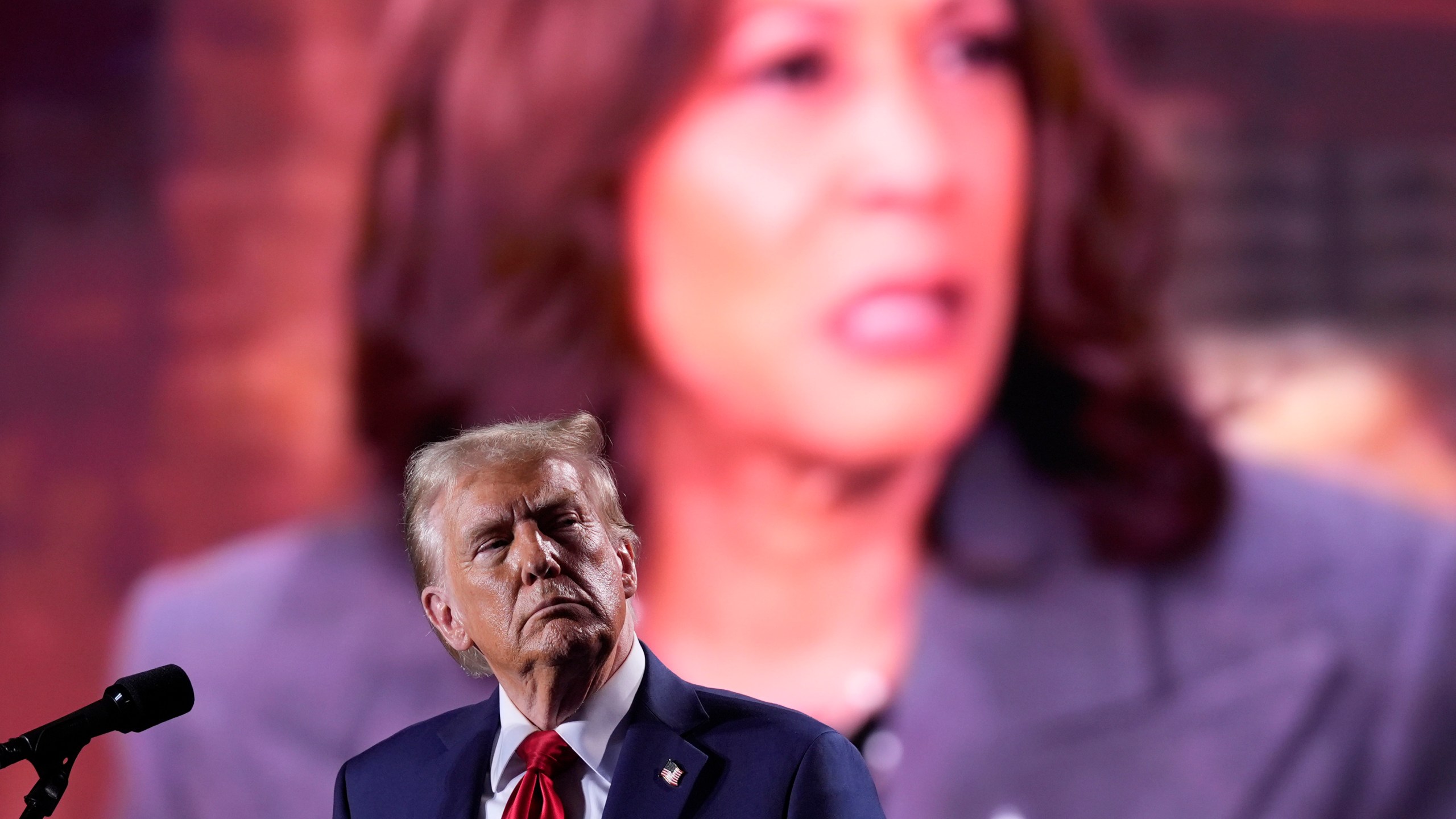 Republican presidential nominee former President Donald Trump watches as a video featuring Democratic presidential nominee Vice President Kamala Harris plays during a campaign event, Friday, Oct. 18, 2024 in Detroit. (AP Photo/Evan Vucci)