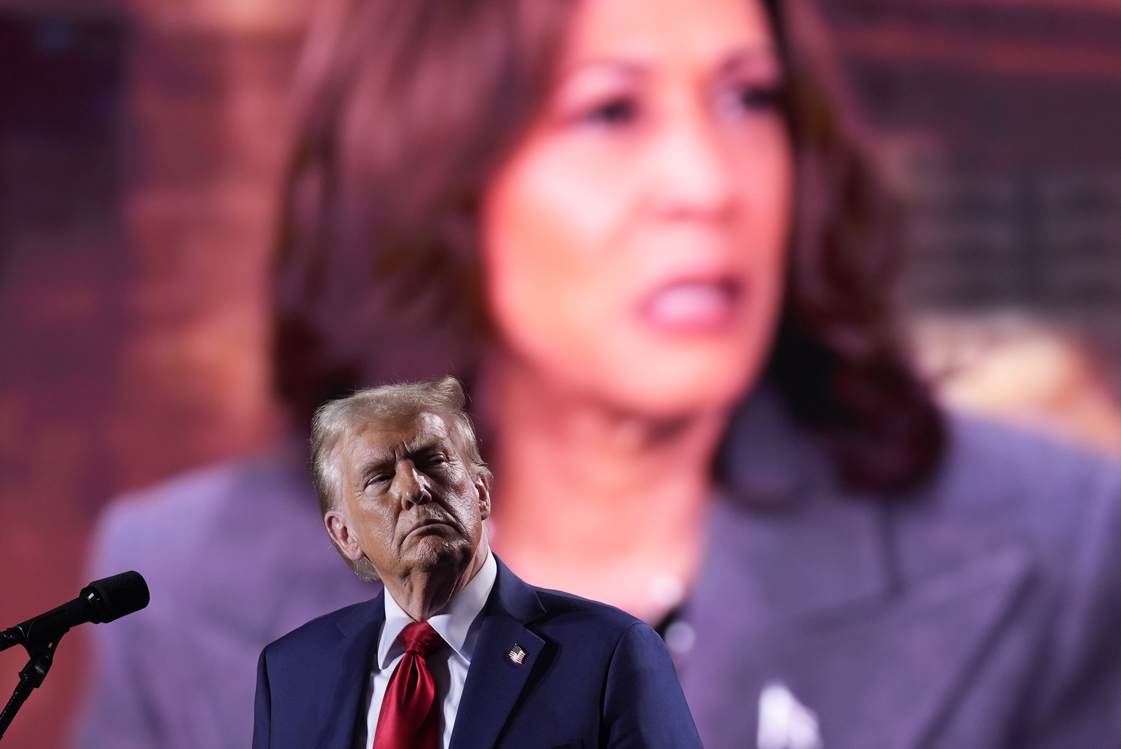 Republican presidential nominee former President Donald Trump watches as a video featuring Democratic presidential nominee Vice President Kamala Harris plays during a campaign event, Friday, Oct. 18, 2024 in Detroit. (AP Photo/Evan Vucci)