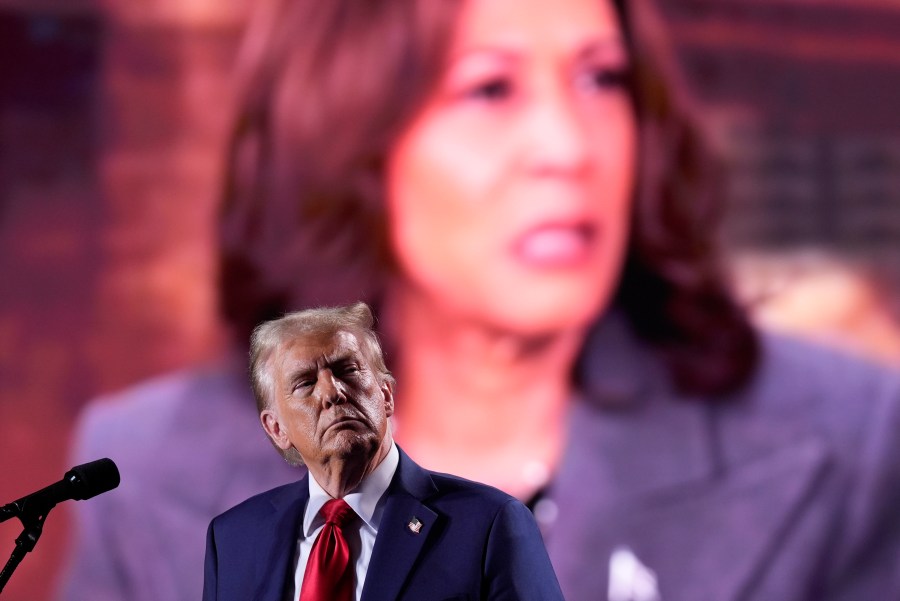 Republican presidential nominee former President Donald Trump watches as a video featuring Democratic presidential nominee Vice President Kamala Harris plays during a campaign event, Friday, Oct. 18, 2024 in Detroit. (AP Photo/Evan Vucci)