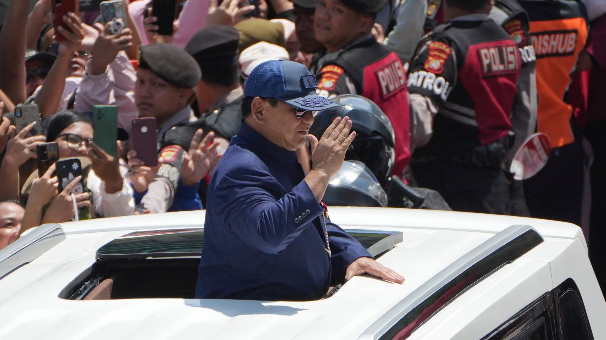 Newly-inaugurated Indonesian President Prabowo Subianto, center, salutes as he greets supporters after being sworn in as the country's eighth president in Jakarta, Indonesia, Sunday, Oct. 20, 2024. (AP Photo/Dita Alangkara)