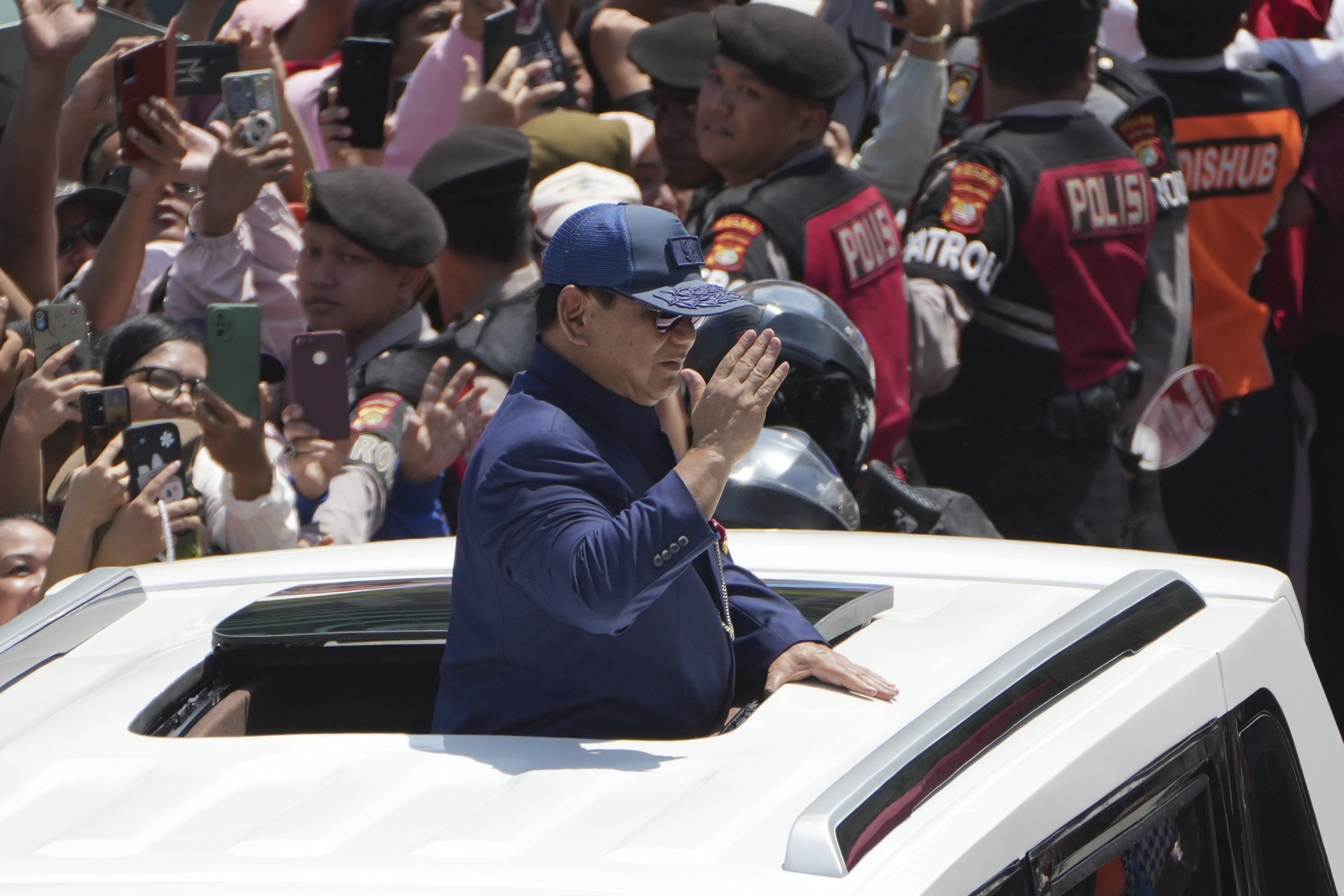 Newly-inaugurated Indonesian President Prabowo Subianto, center, salutes as he greets supporters after being sworn in as the country's eighth president in Jakarta, Indonesia, Sunday, Oct. 20, 2024. (AP Photo/Dita Alangkara)