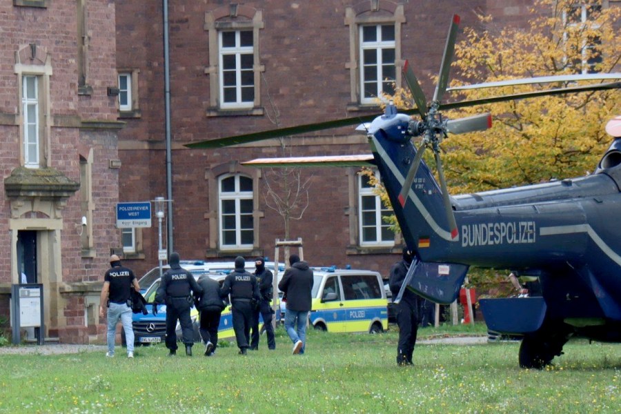 Police officers escort a Libyan national with suspected ties to the extremist group Islamic State who was allegedly planning an attack on the Israeli Embassy in Berlin, in Karlsruhe, Germany, Sunday Oct. 20, 2024. (Rene Priebe/dpa via AP)