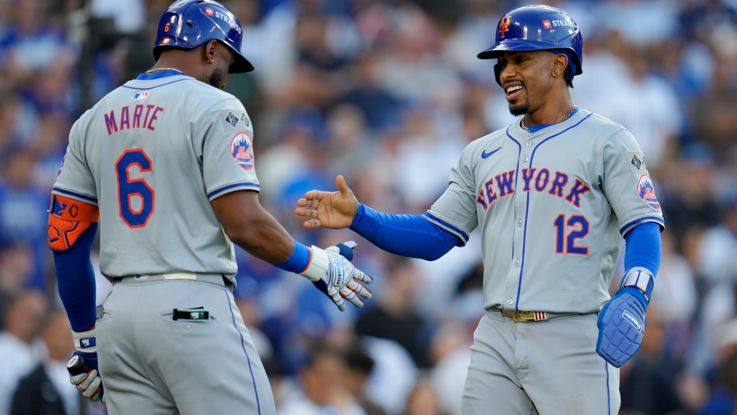 New York Mets' Francisco Lindor celebrates with Starling Marte after scoring on a throwing error by Los Angeles Dodgers second baseman Chris Taylor during the first inning in Game 6 of a baseball NL Championship Series, Sunday, Oct. 20, 2024, in Los Angeles. (AP Photo/Julio Cortez)