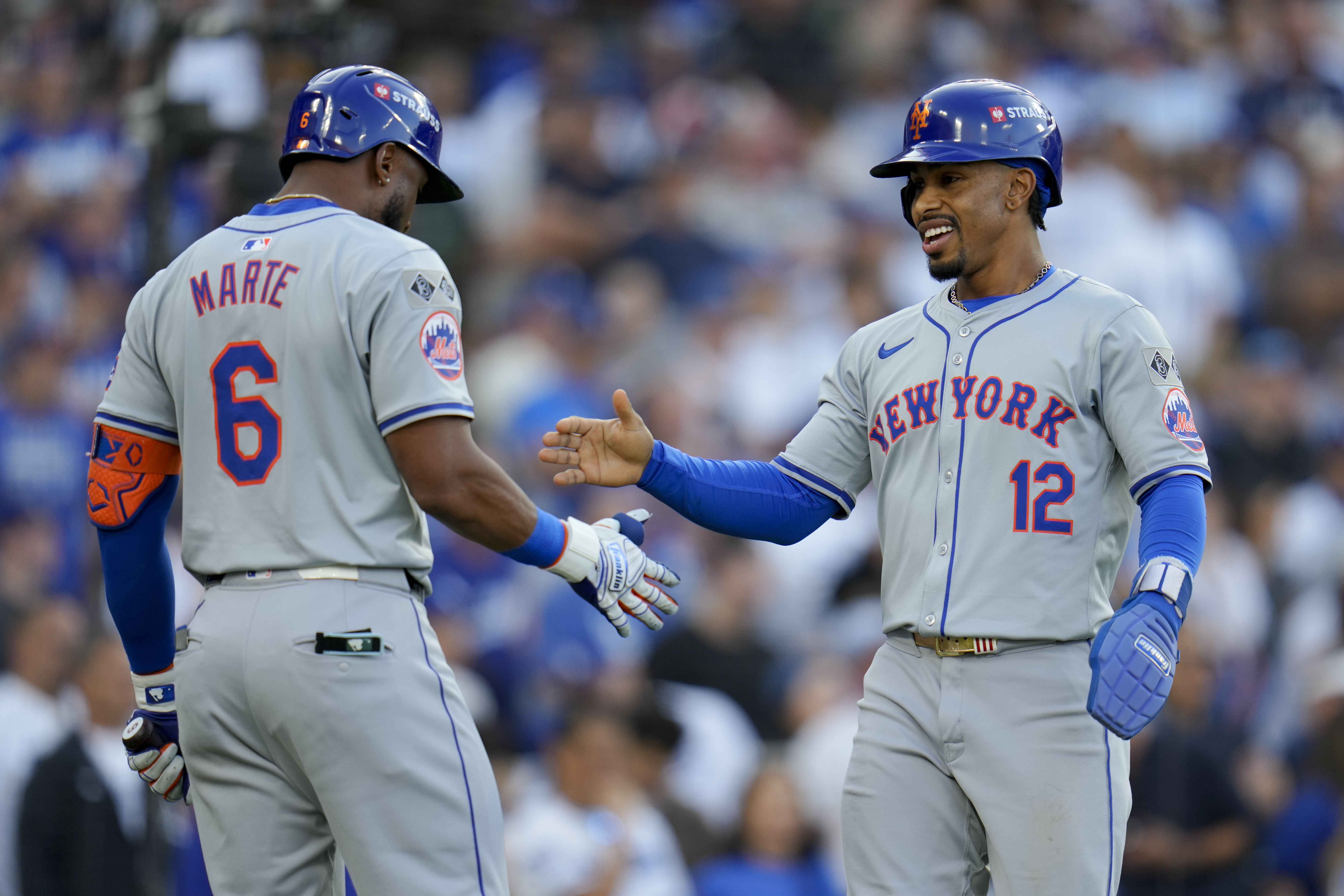 New York Mets' Francisco Lindor celebrates with Starling Marte after scoring on a throwing error by Los Angeles Dodgers second baseman Chris Taylor during the first inning in Game 6 of a baseball NL Championship Series, Sunday, Oct. 20, 2024, in Los Angeles. (AP Photo/Julio Cortez)