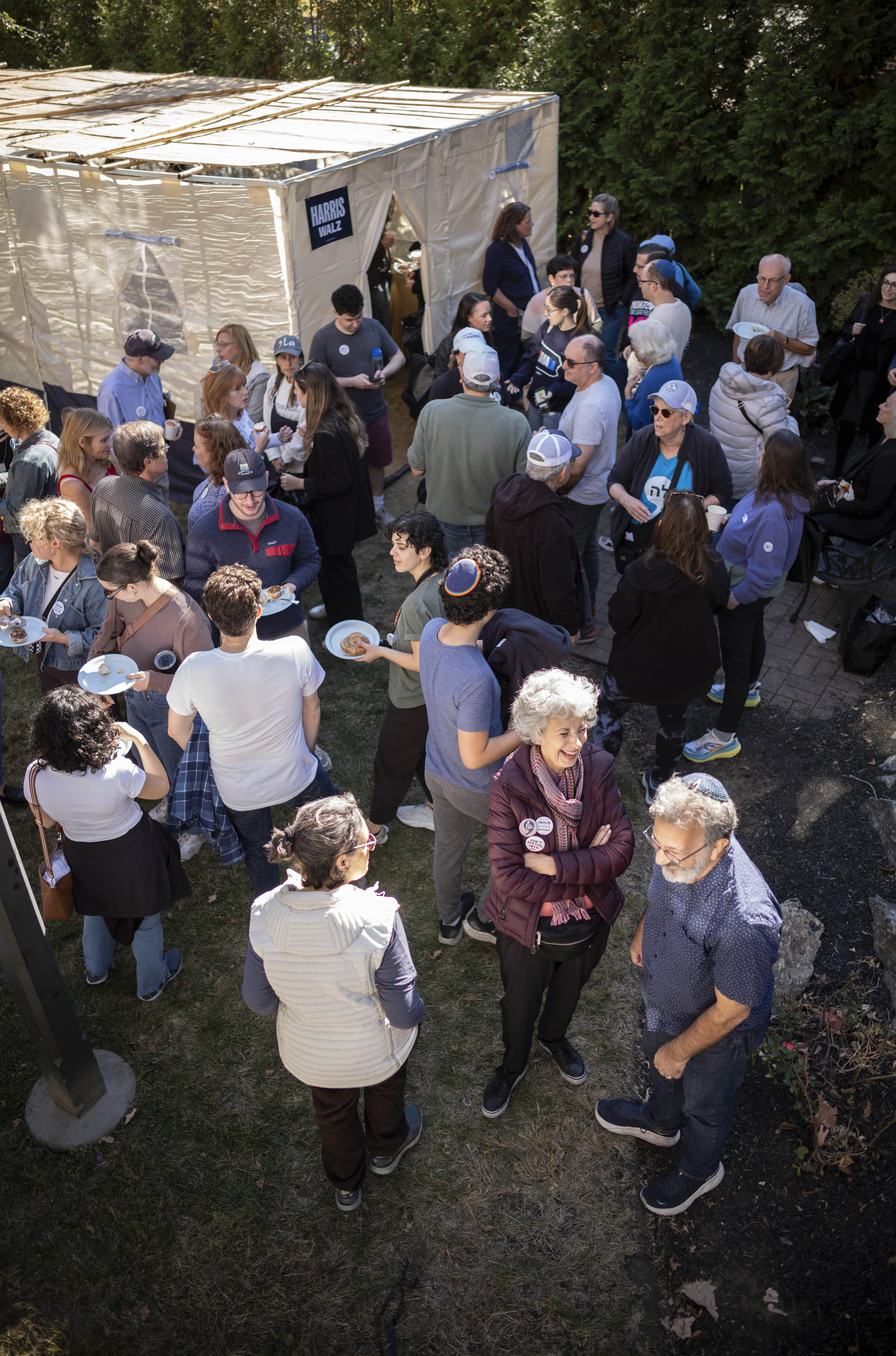 Supporters of Democratic presidential nominee Vice President Kamala Harris gather around a Sukkot before going door to door canvassing Jewish voters during the Jewish holiday in Bala Cynwyd, Pa, Sunday, Oct. 20, 2024. (AP Photo/Laurence Kesterson)