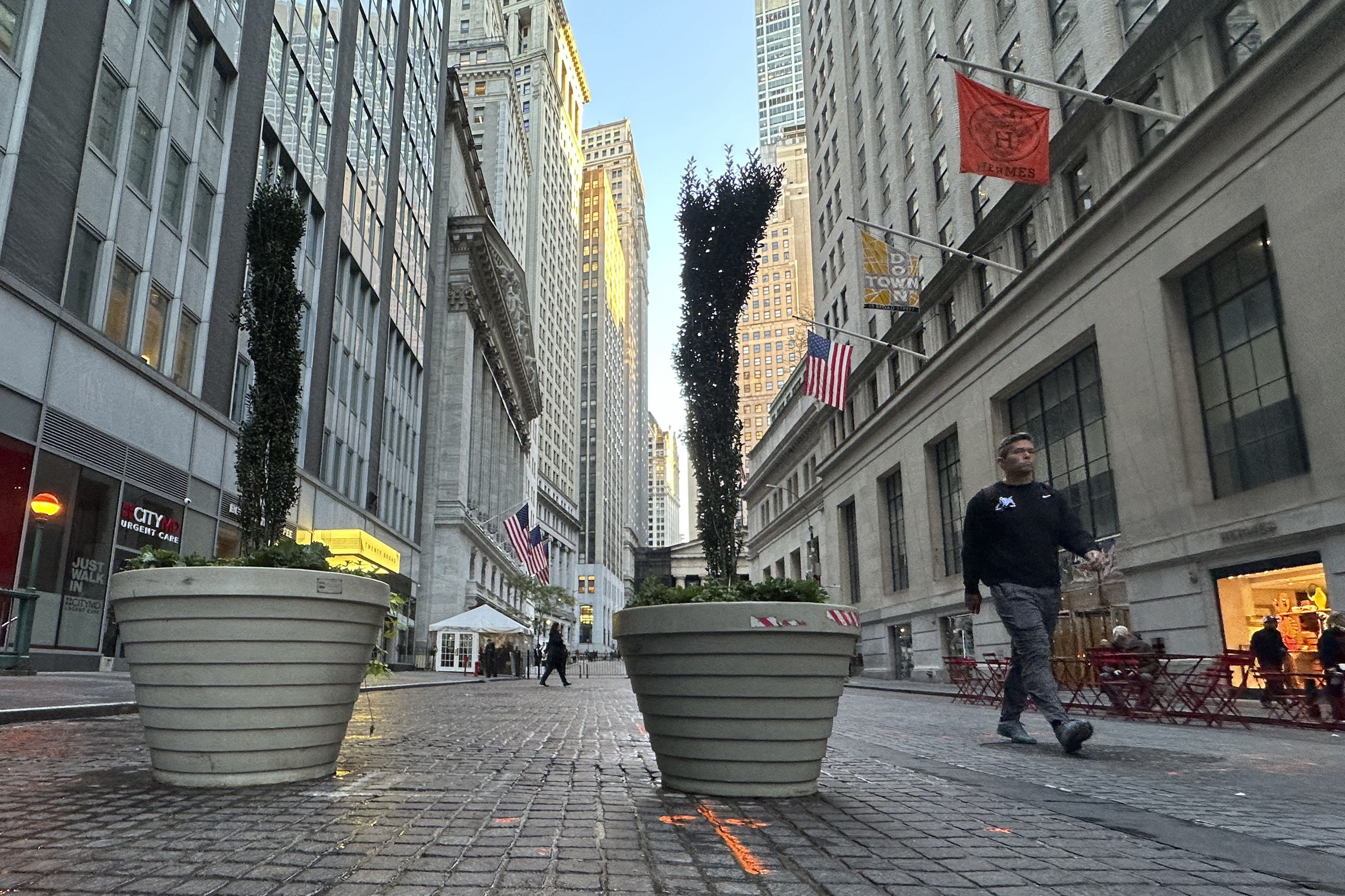 FILE - People pass the New York Stock Exchange, at rear, in New York's Financial District on Oct. 16, 2024. (AP Photo/Peter Morgan, File)