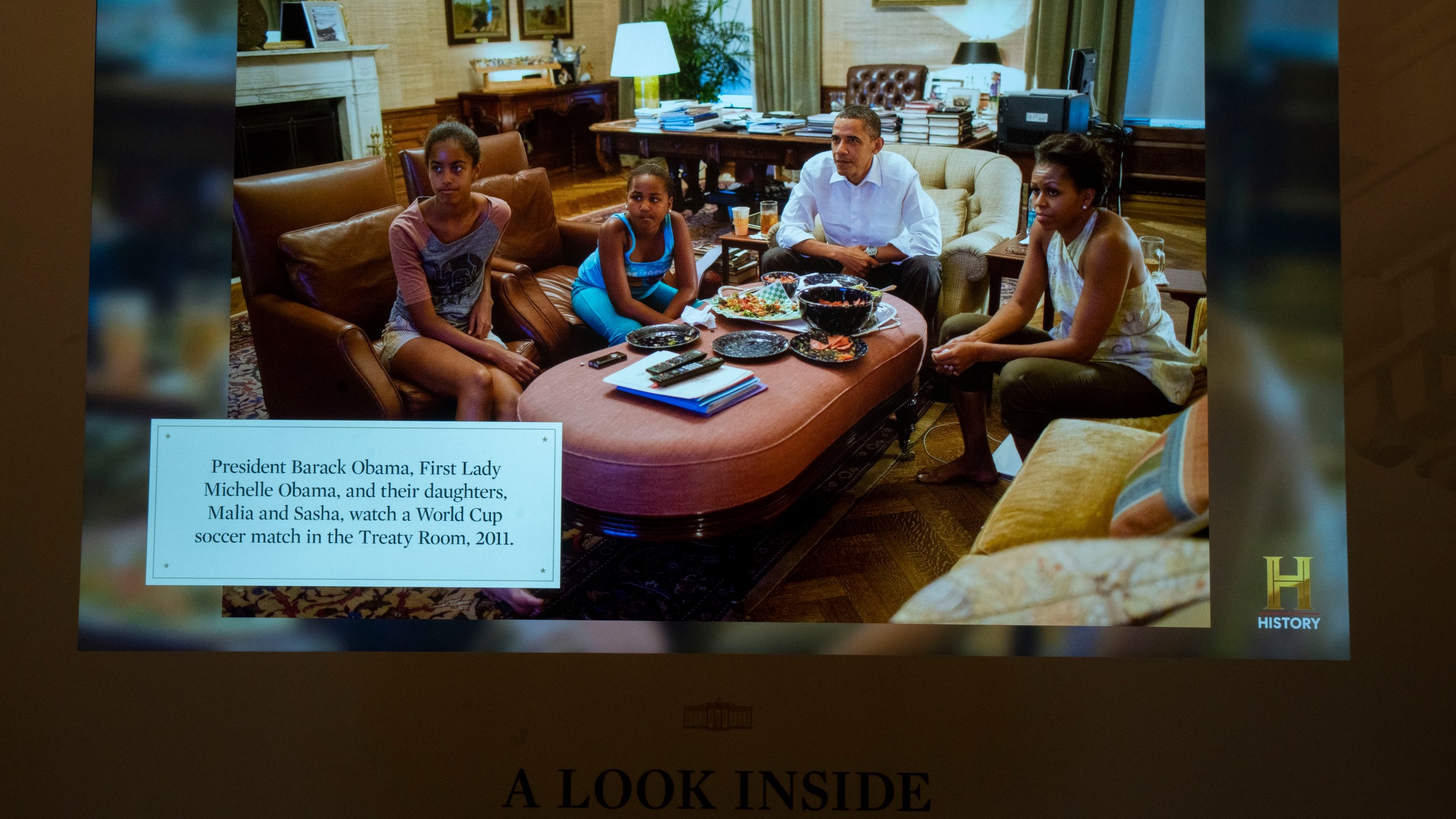 "A look inside the White House" digital frame that changes picture display every minute, shows on Friday, Oct. 18, 2024 in Washington, a captioned picture of former President Barack Obama and his family in the Treaty Room. (AP Photo/Manuel Balce Ceneta)