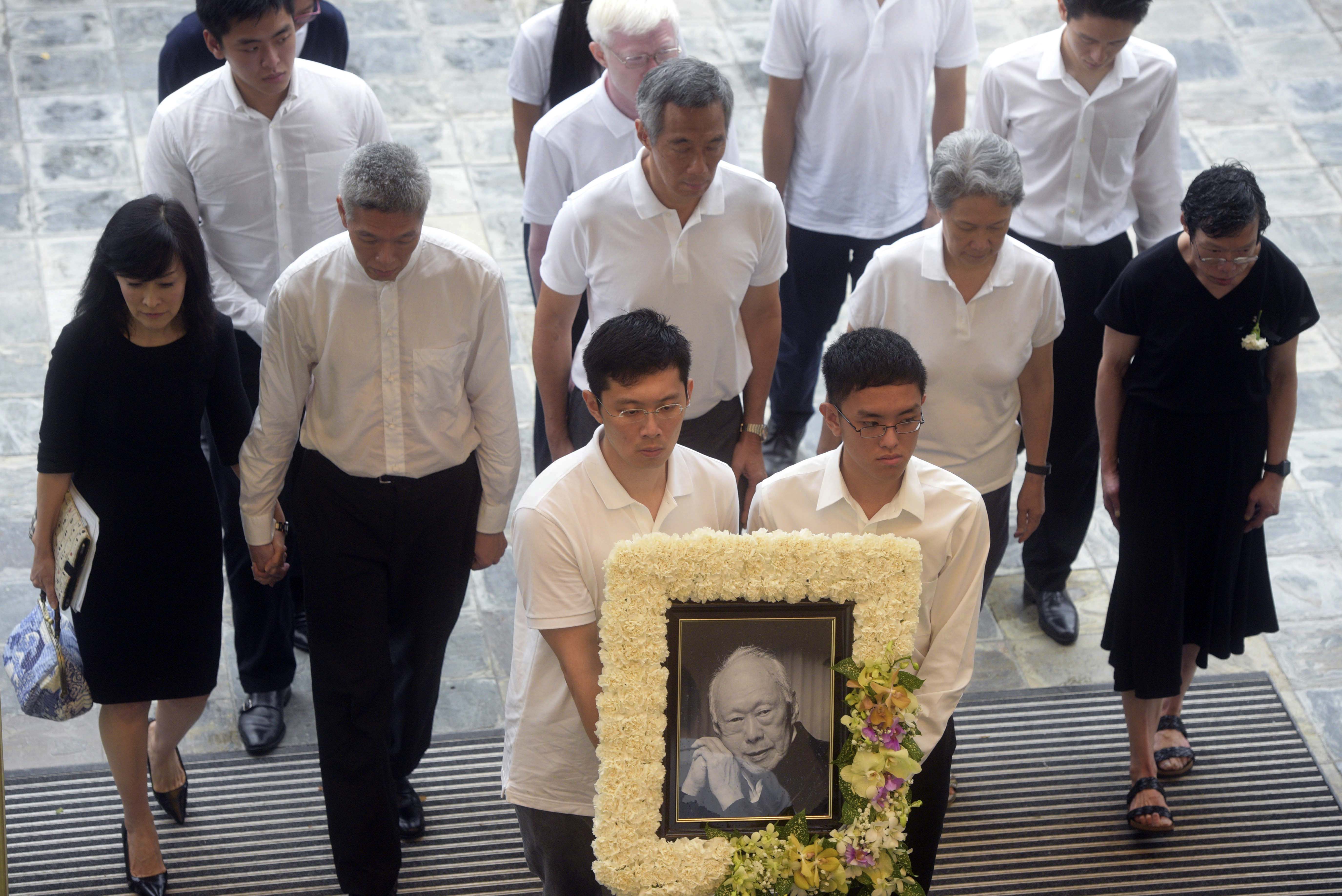 FILE - Family members, second row left to right, Lee Suet Fern, son, (Lee Hsien Yang's wife), Lee Hsien Yang, Lee Hsien Loong, son and current prime minister, Ho Ching (Lee Hsien Loong's wife) and Lee Wei Ling, daughter, of the late Lee Kuan Yew arrive with his portrait at the start of the state funeral at the University Cultural Center in Singapore, Sunday, March 29, 2015. (AP Photo/Joseph Nair, File)