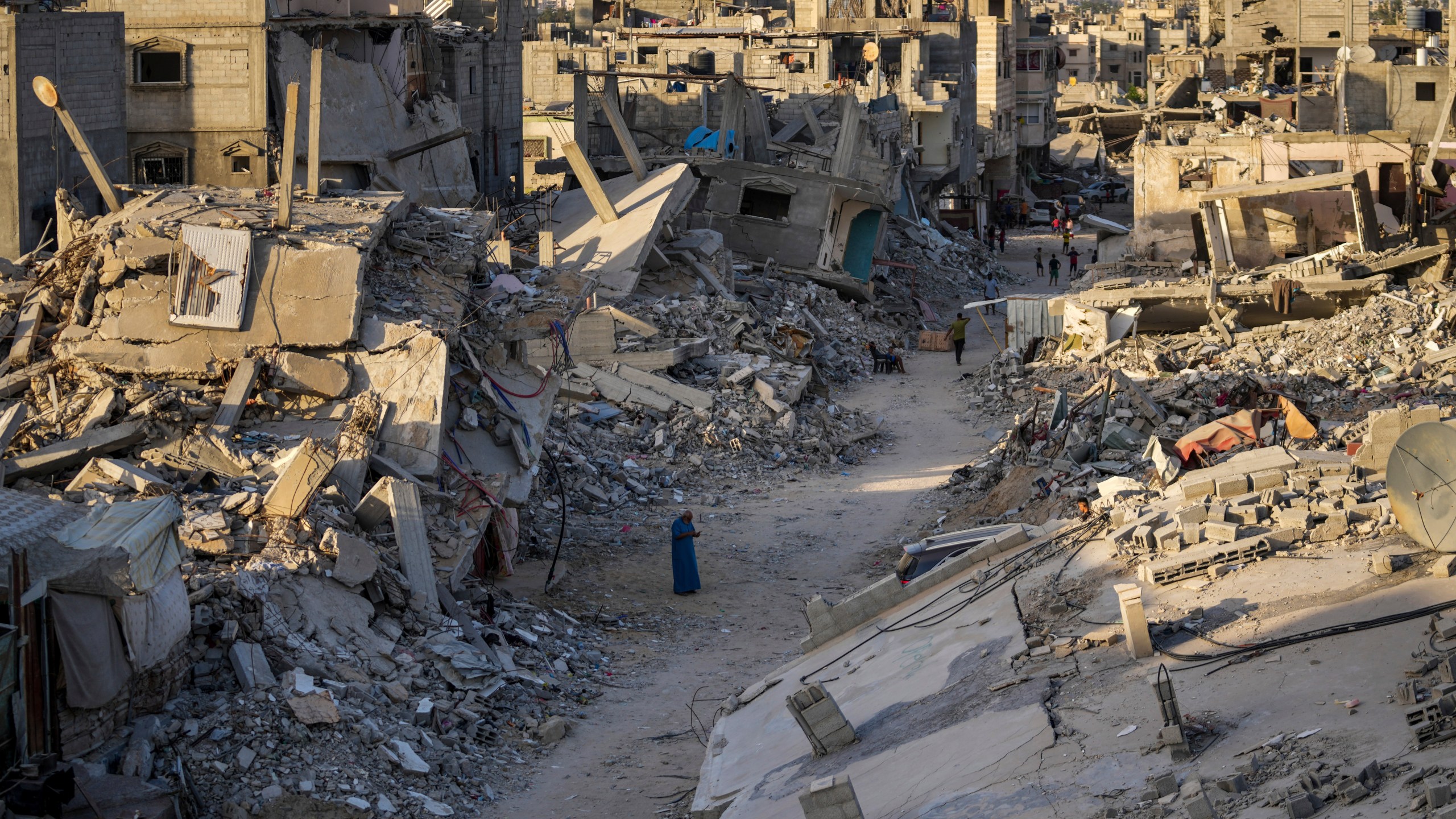 FILE - Palestinians walk through the destruction left by the Israeli air and ground offensive on Khan Younis, Gaza Strip, on Sept. 12, 2024. (AP Photo/Abdel Kareem Hana, File)