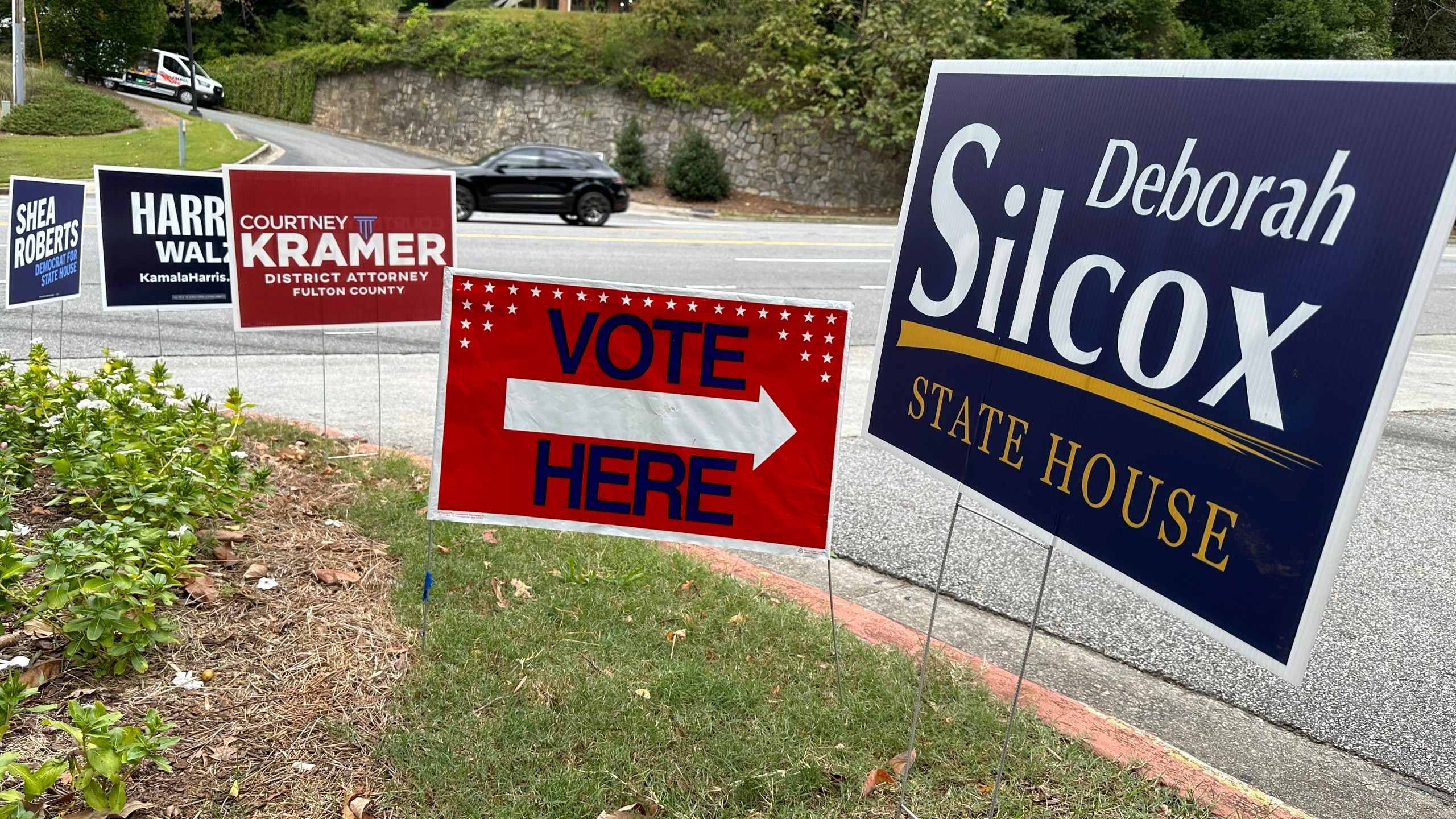 Signs entice voters in the Atlanta suburb of Sandy Springs, Ga., Tuesday, Oct. 15, 2024, the first day of early in-person voting in Georgia. (AP Photo/Jeff Amy)