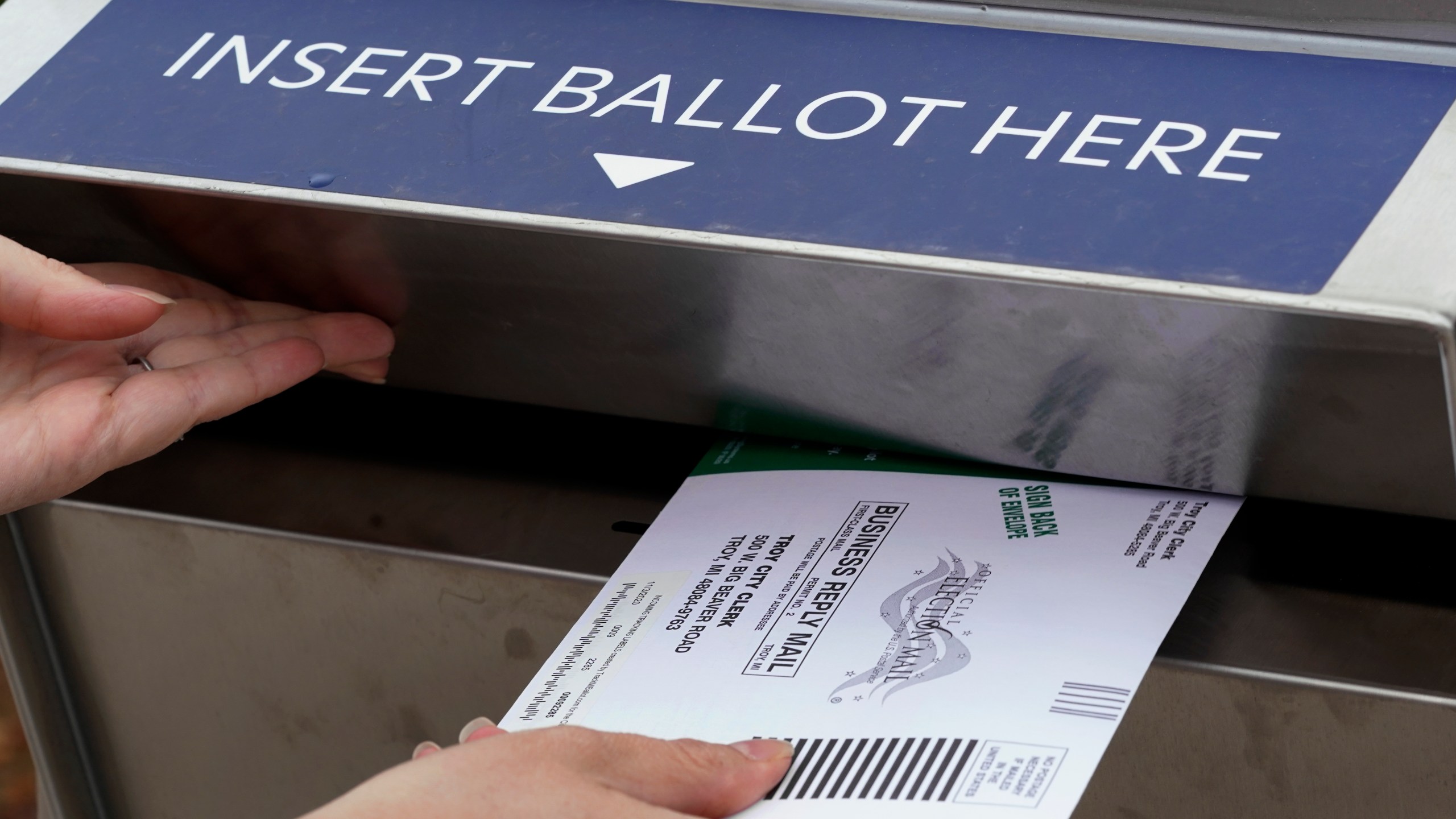 FILE - A Michigan voter inserts her absentee voter ballot into a drop box in Troy, Mich. on Oct. 15, 2020. (AP Photo/Paul Sancya, File)