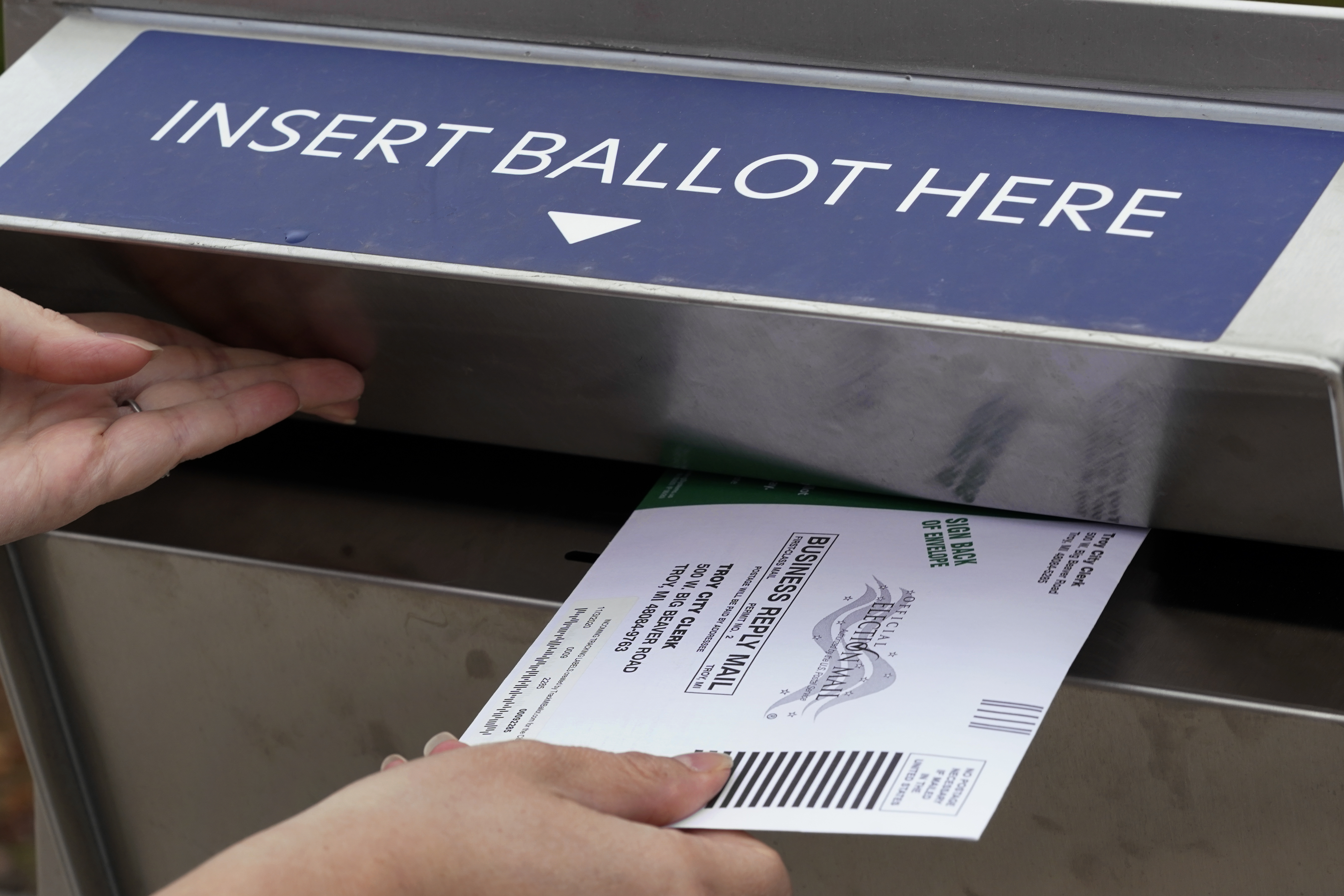 FILE - A Michigan voter inserts her absentee voter ballot into a drop box in Troy, Mich. on Oct. 15, 2020. (AP Photo/Paul Sancya, File)